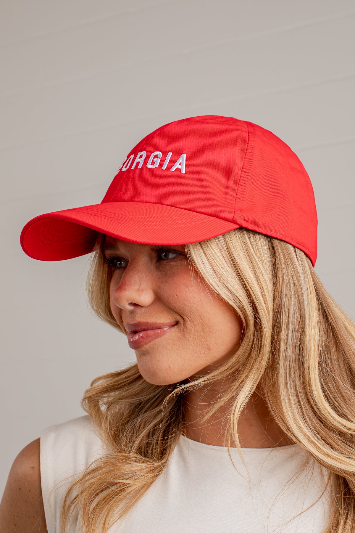A woman wearing a bright red baseball cap with &