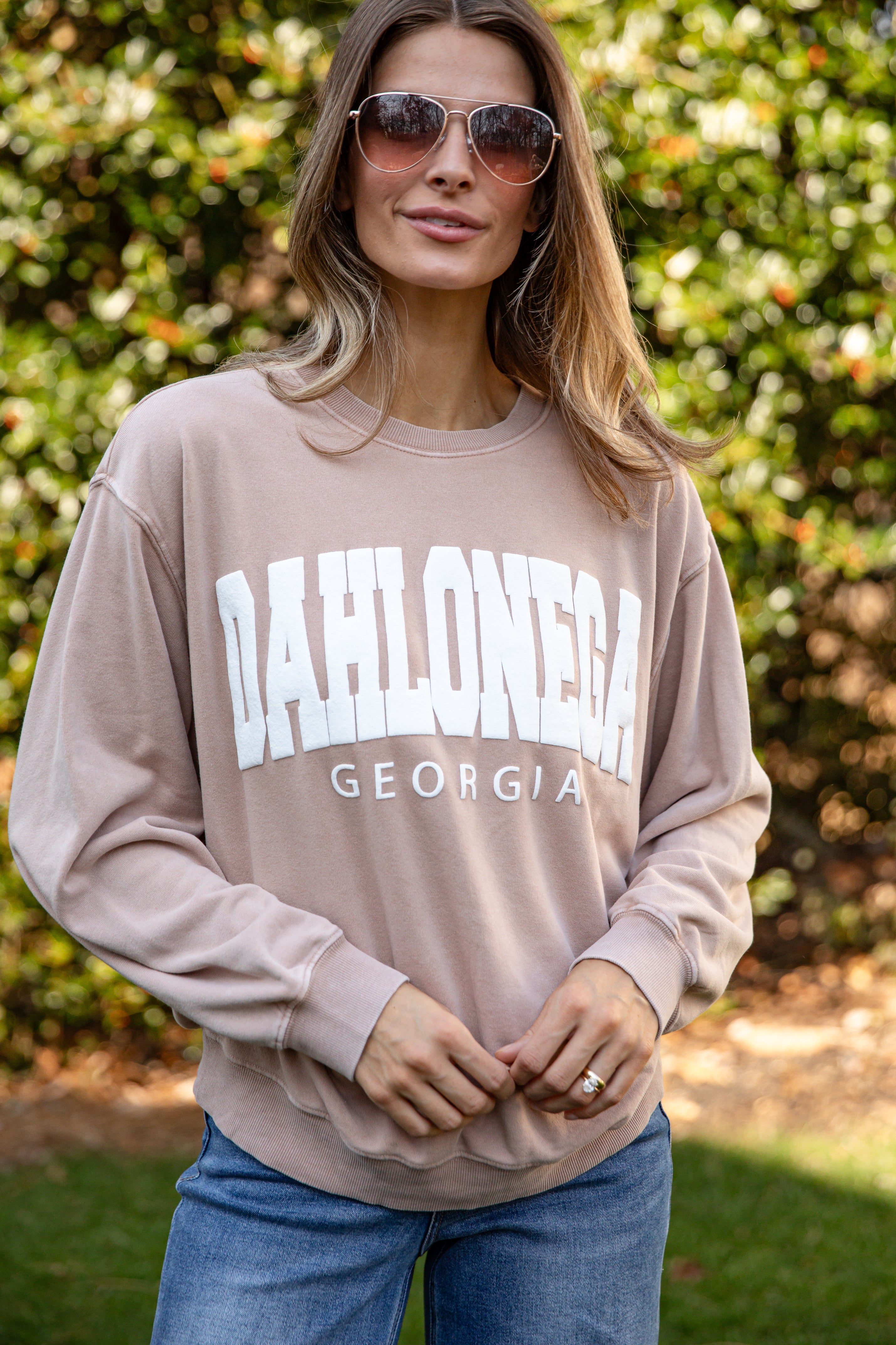 Woman wearing a beige sweatshirt with &