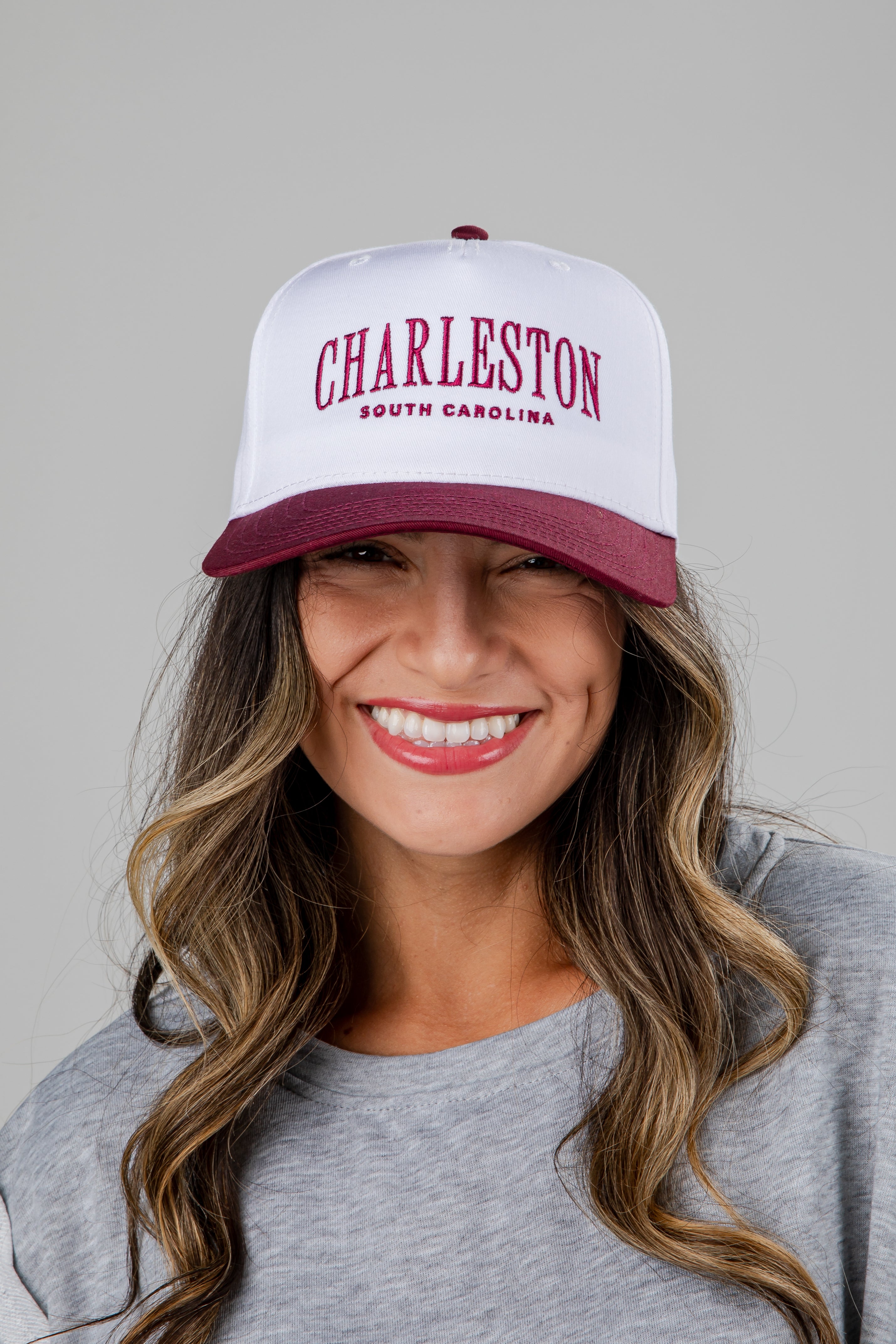 Woman wearing a white and burgundy cap with &
