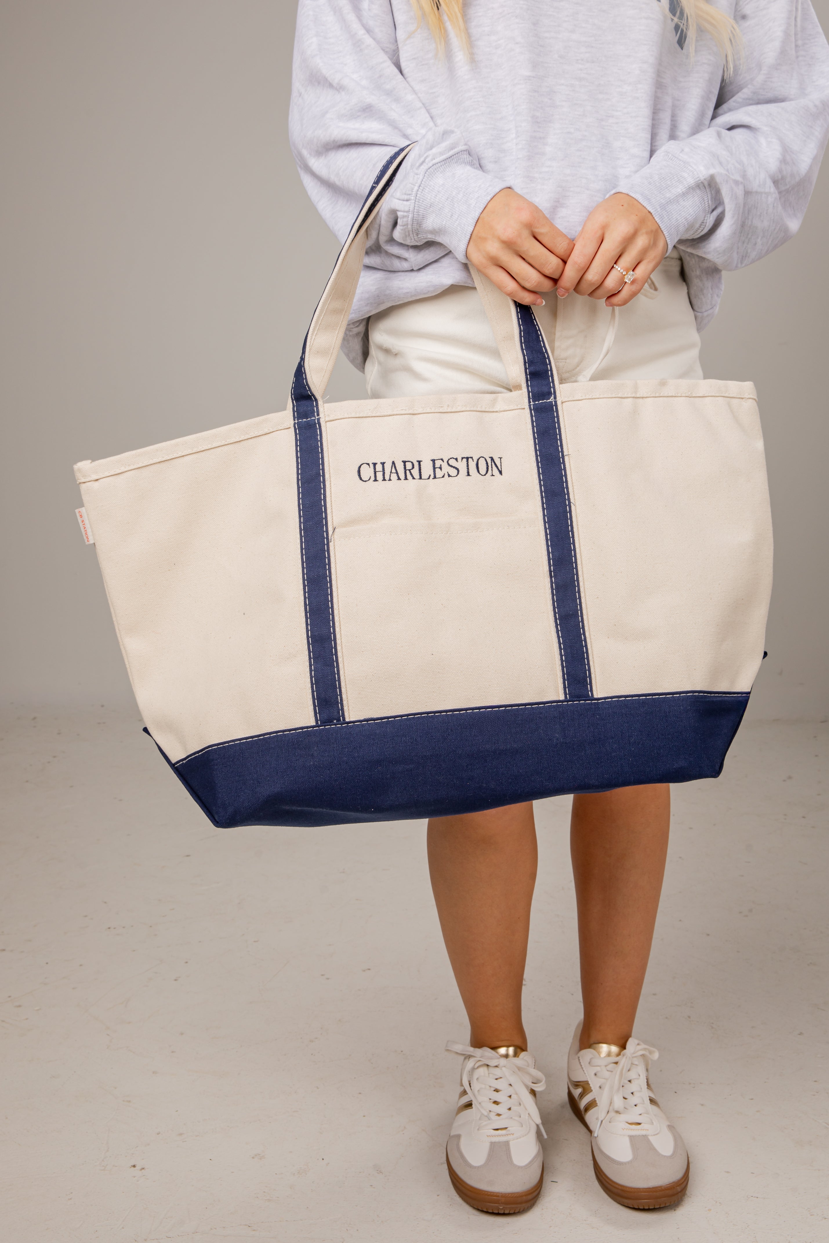 Person holding a white tote bag with blue accents and &