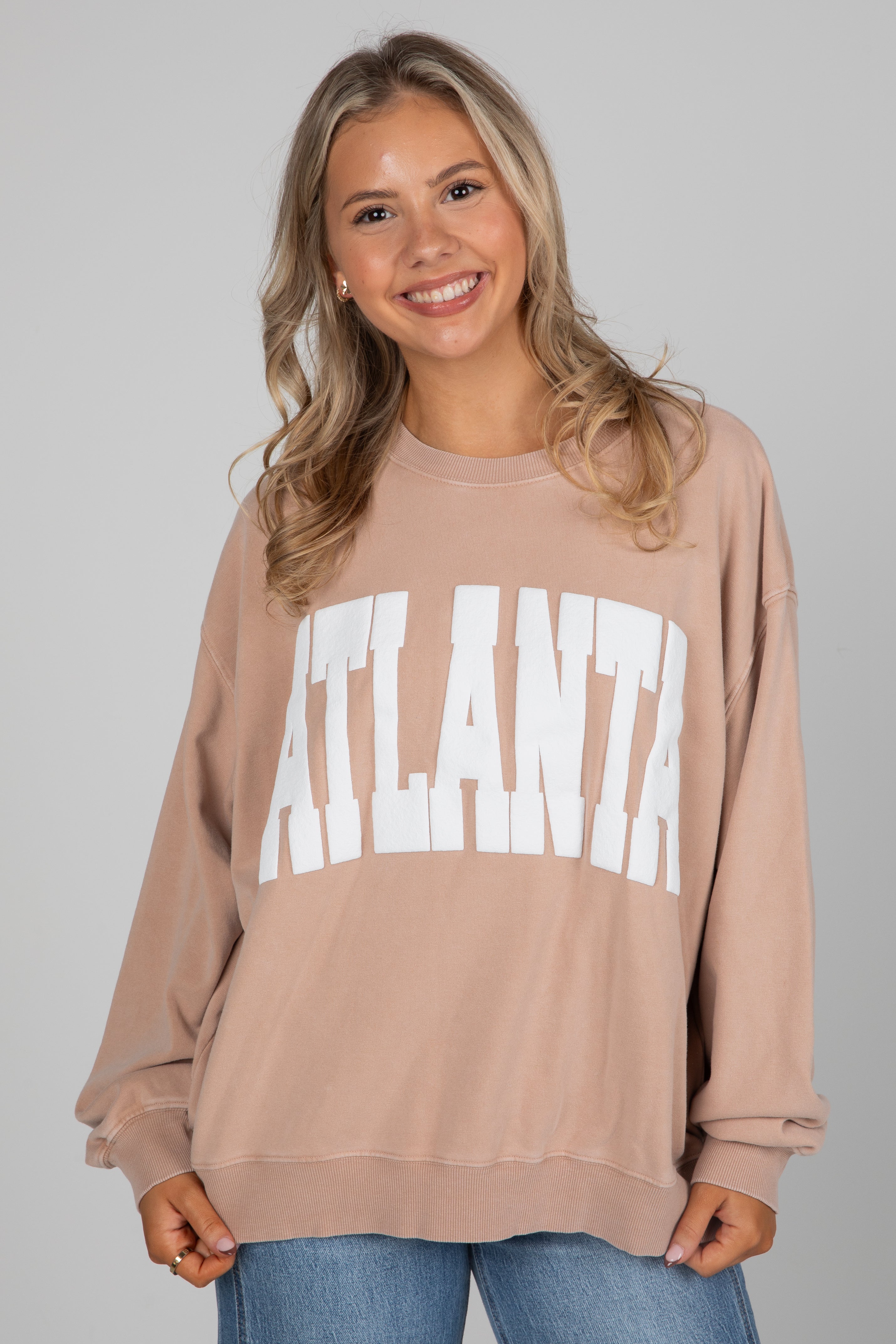 Woman wearing a beige sweatshirt with &