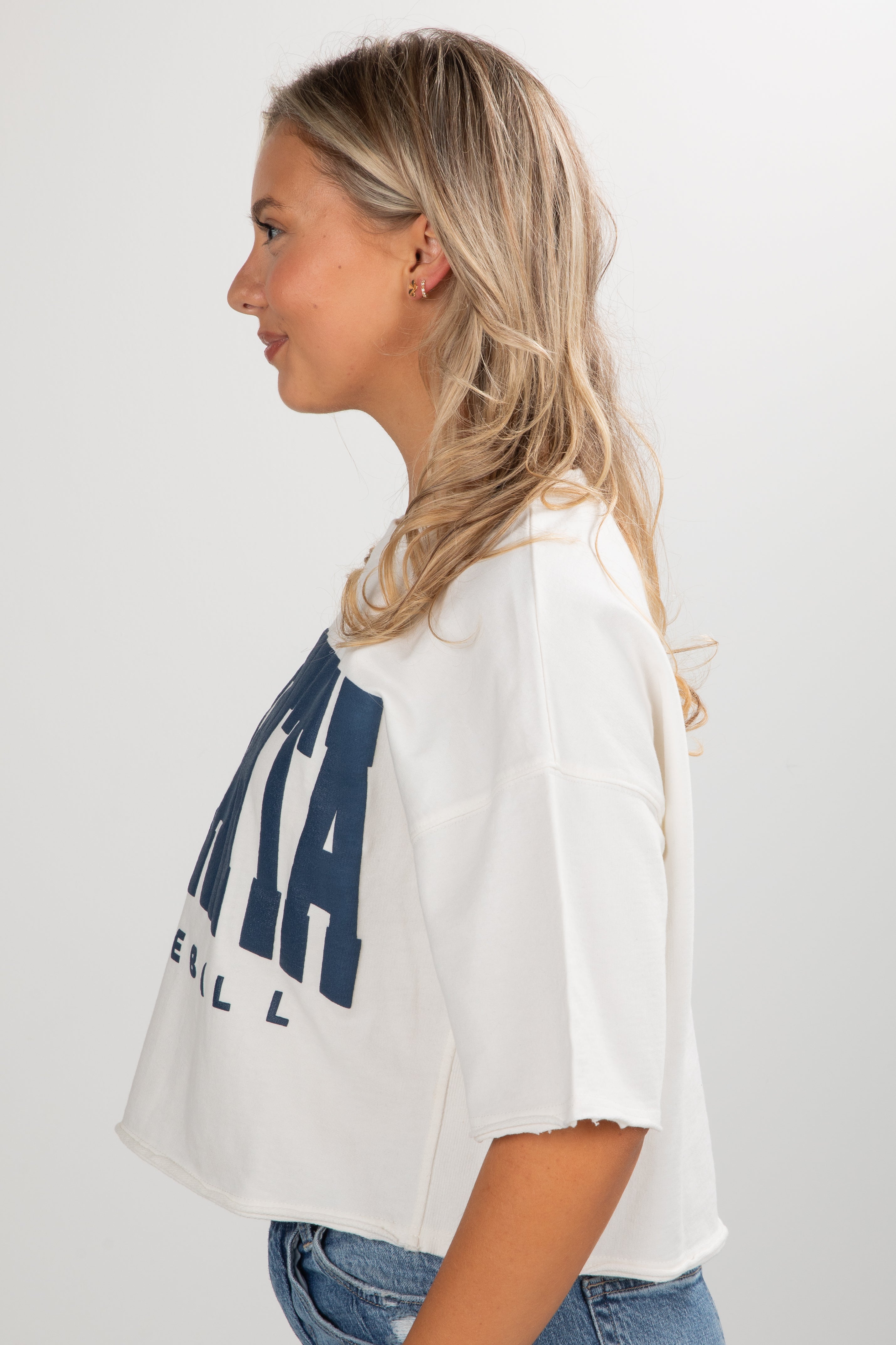 Woman wearing a white t-shirt with blue text on a plain background