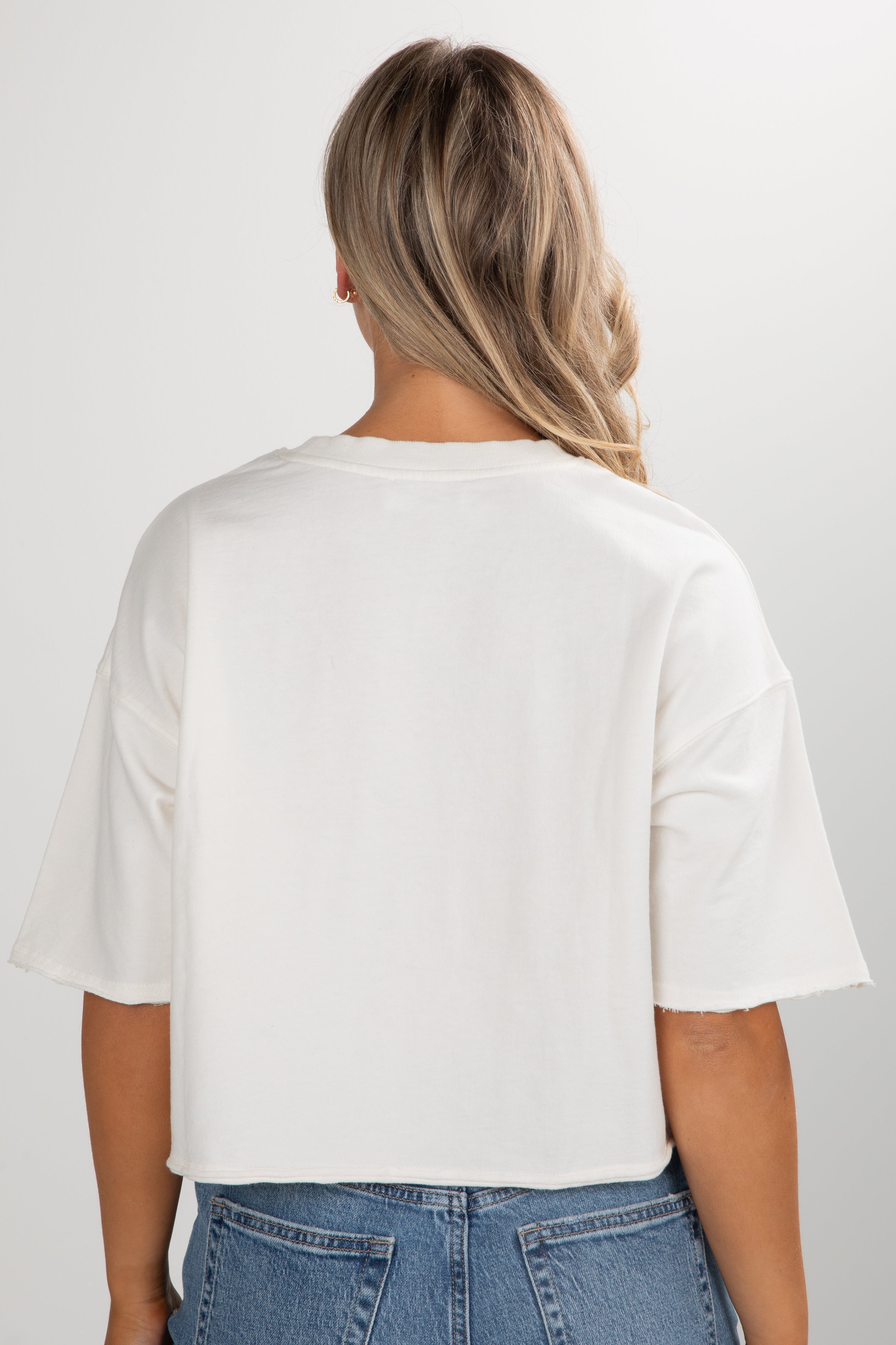 Person wearing a white t-shirt and blue jeans on a plain background