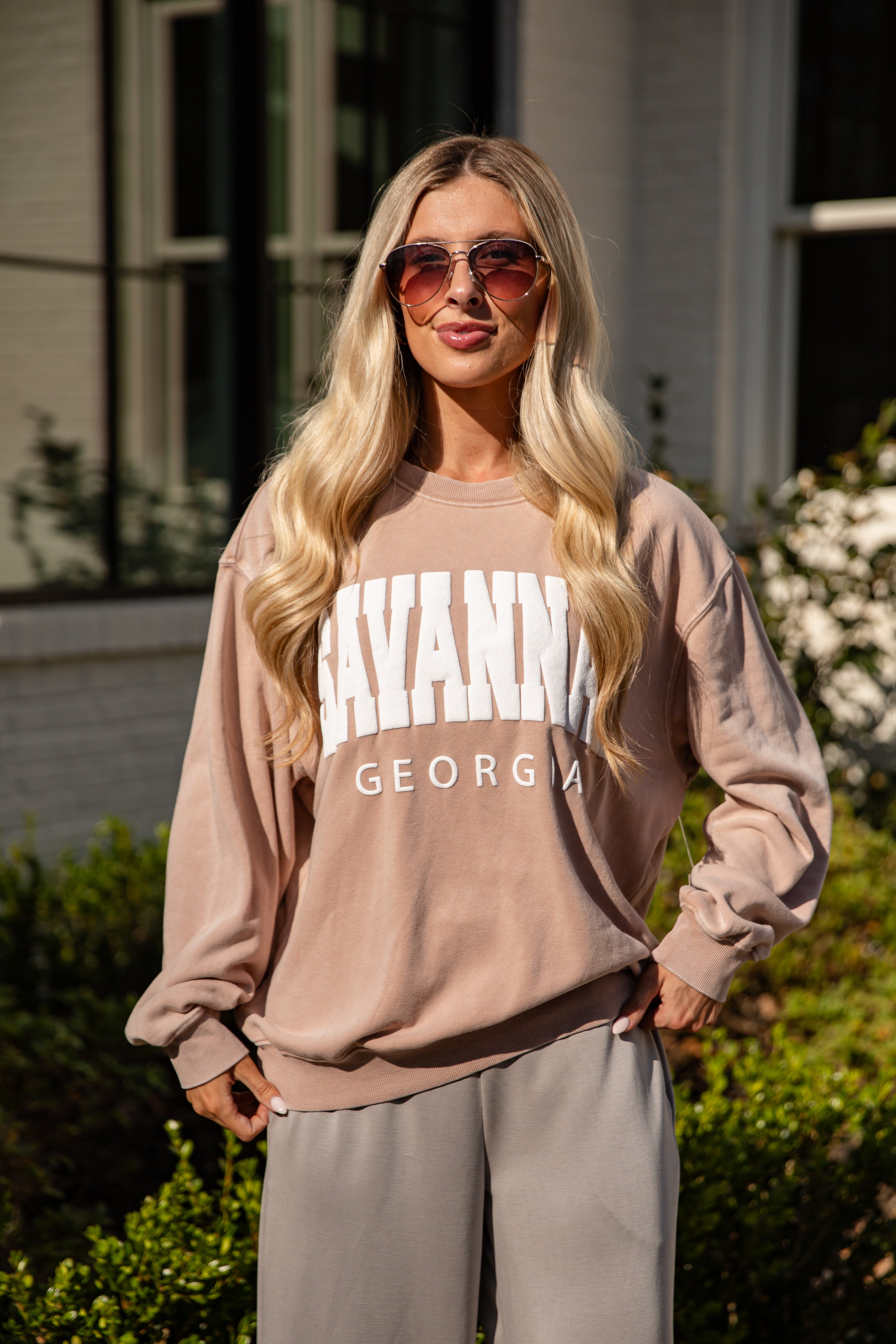 Woman wearing a beige sweatshirt with &