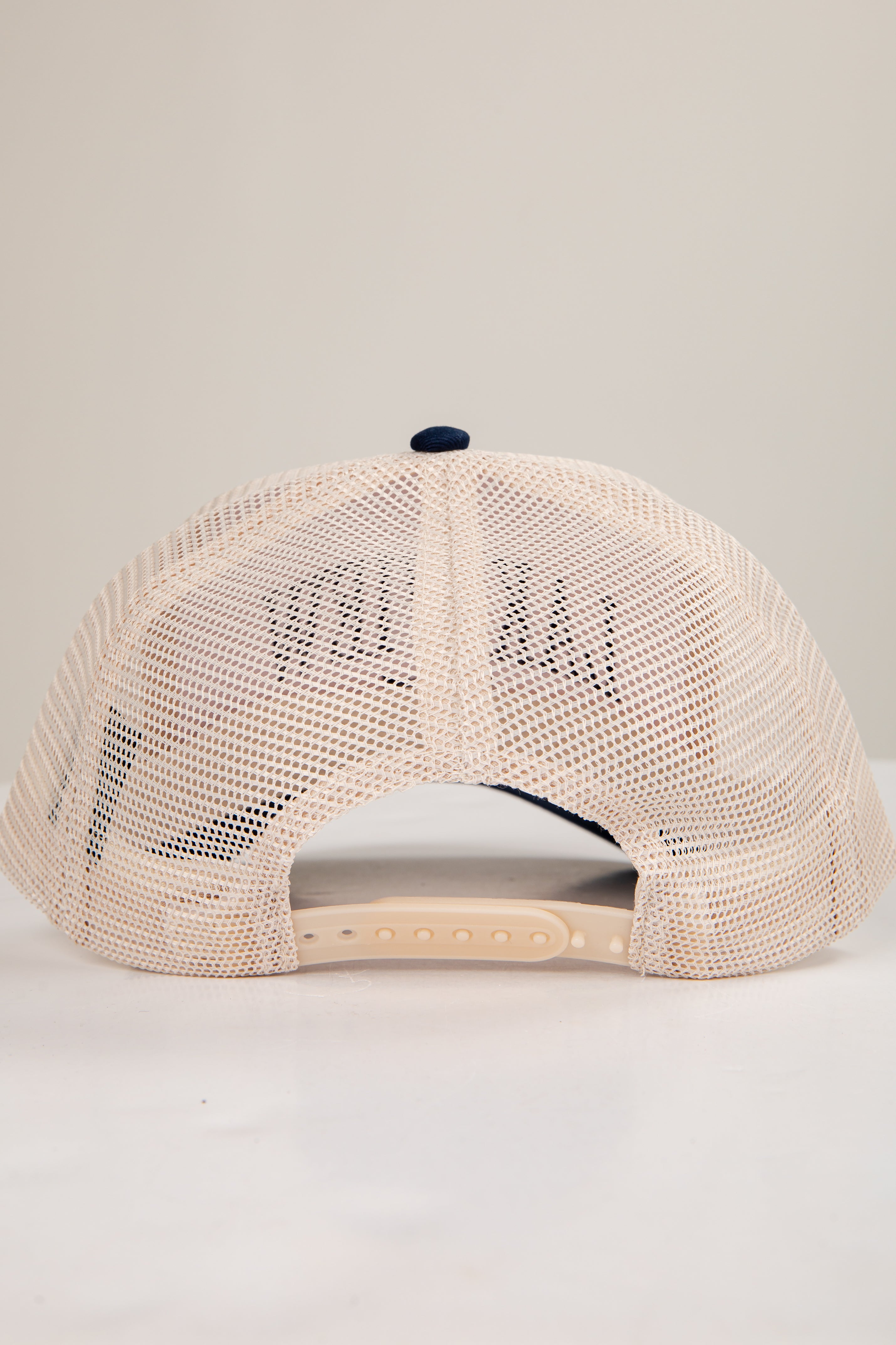 Beige mesh cap with a small logo on a light gray background