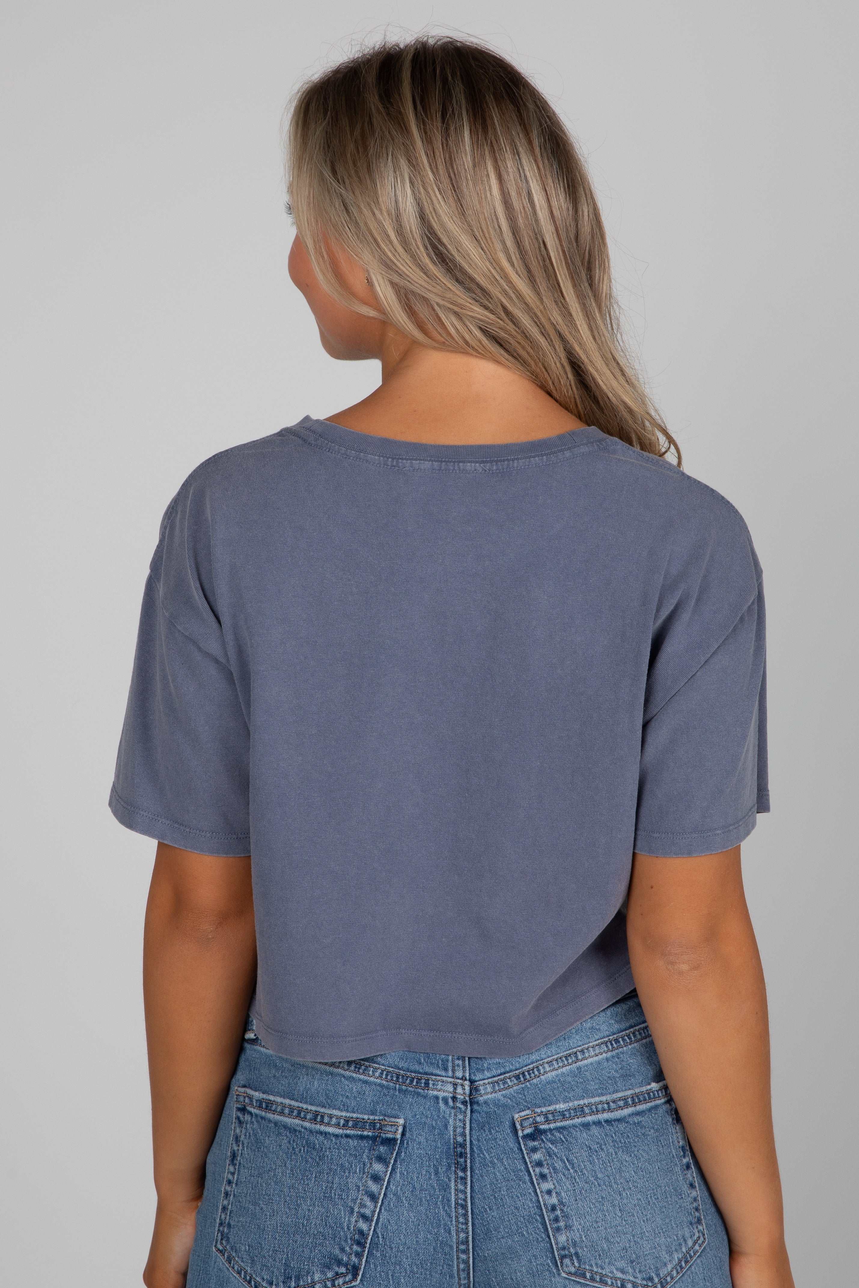 Person wearing a blue t-shirt and jeans on a gray background