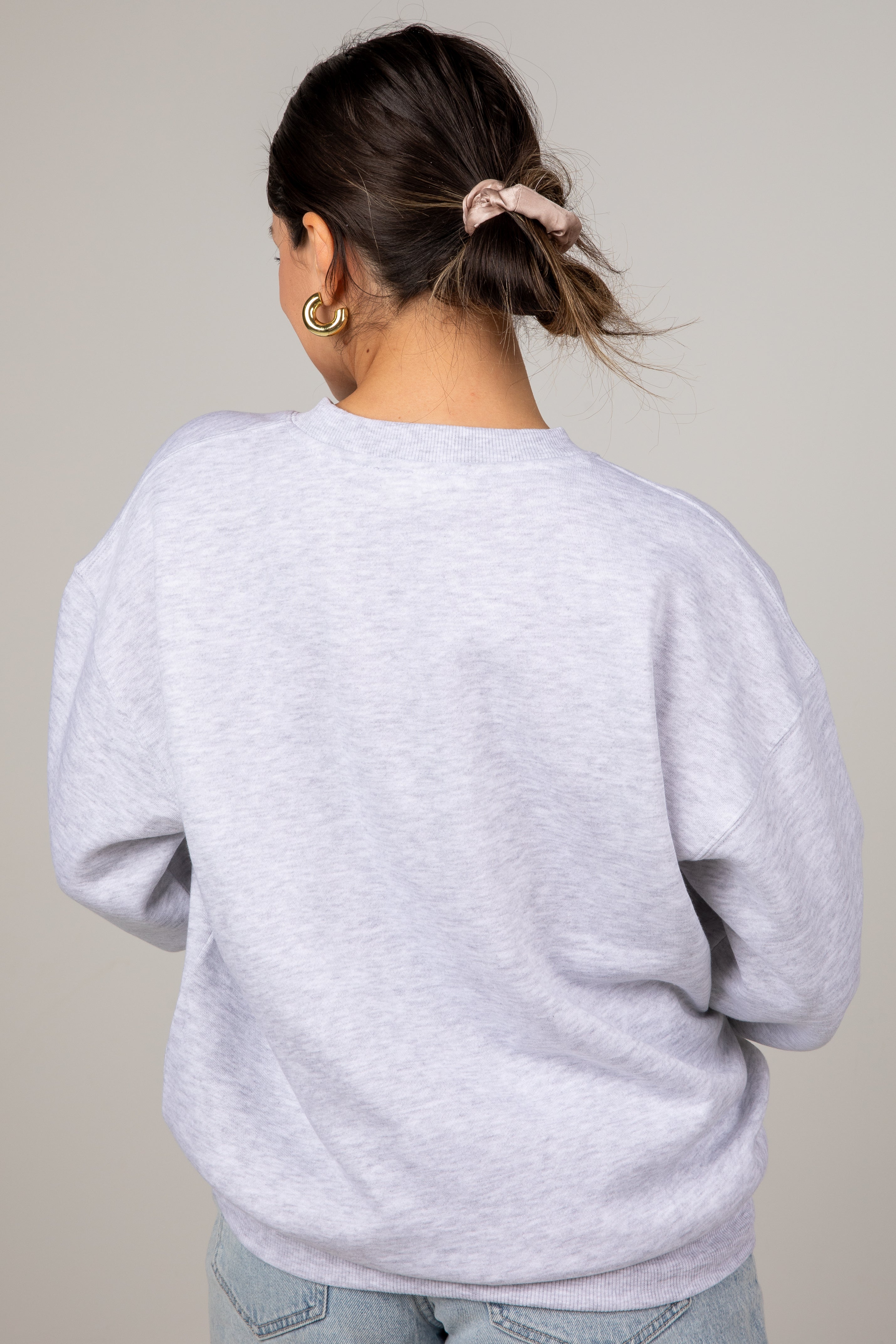 Person wearing a light gray sweatshirt against a plain background