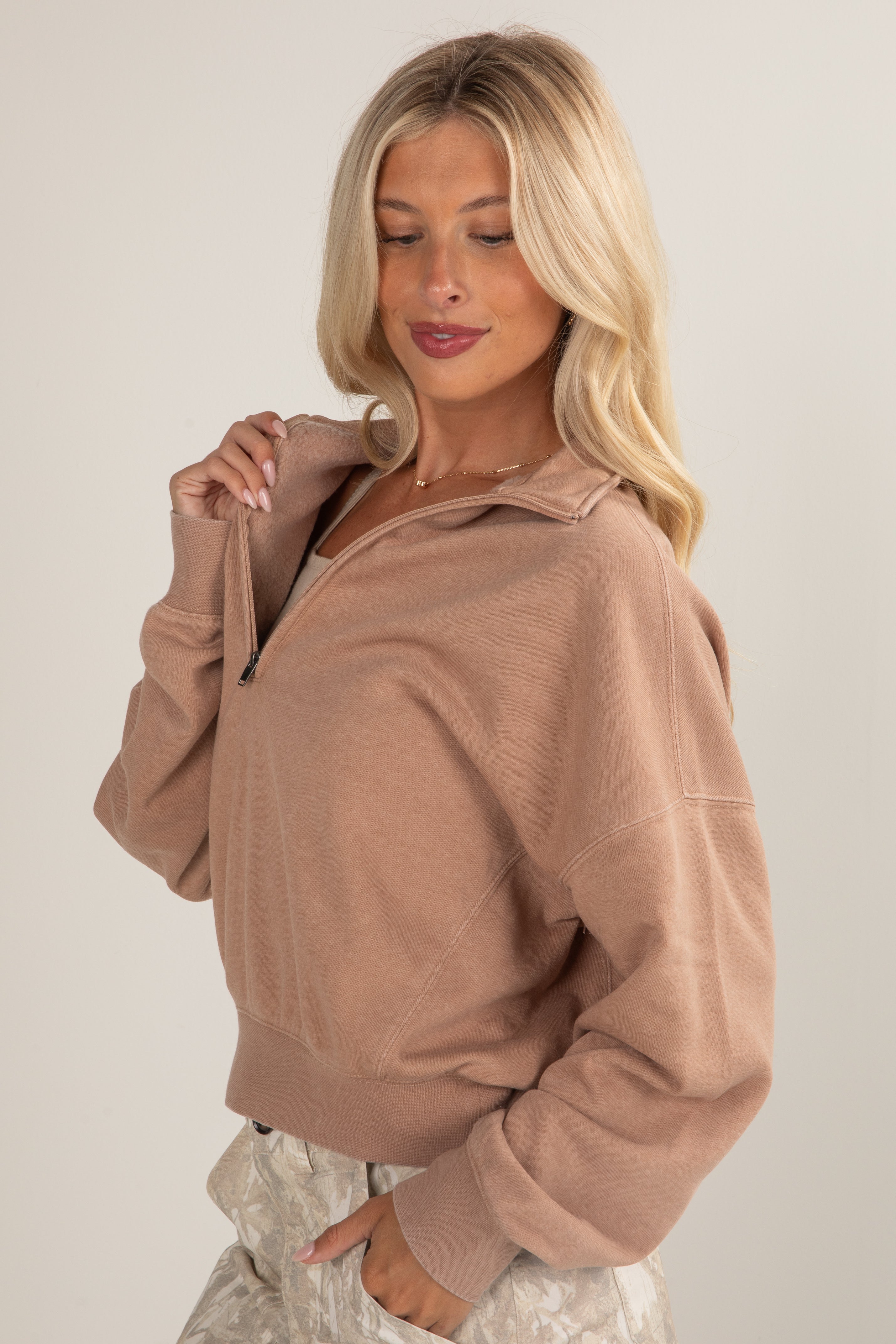 Woman wearing a beige zip-up sweater against a plain background
