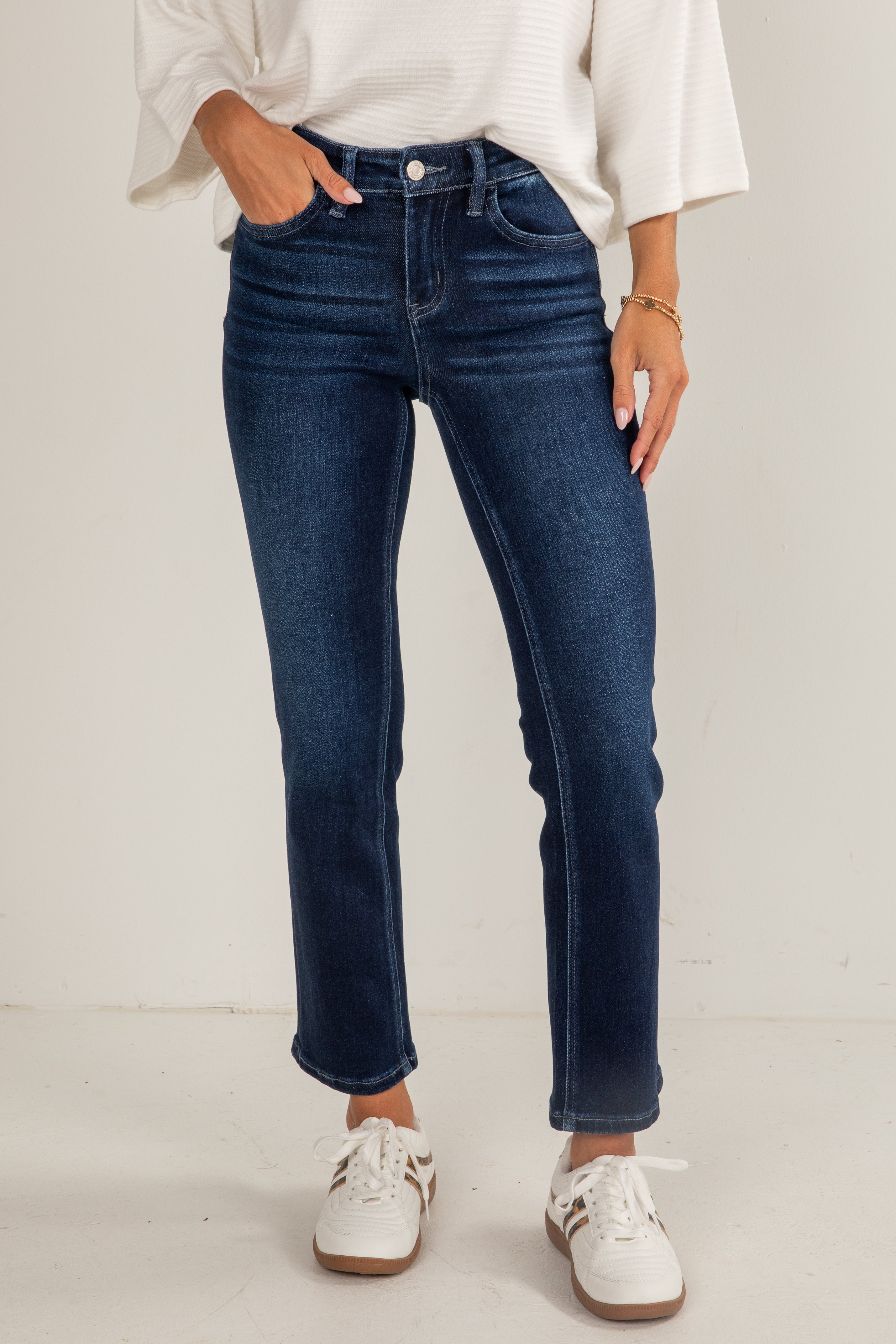 Person wearing blue jeans and a white shirt on a plain background