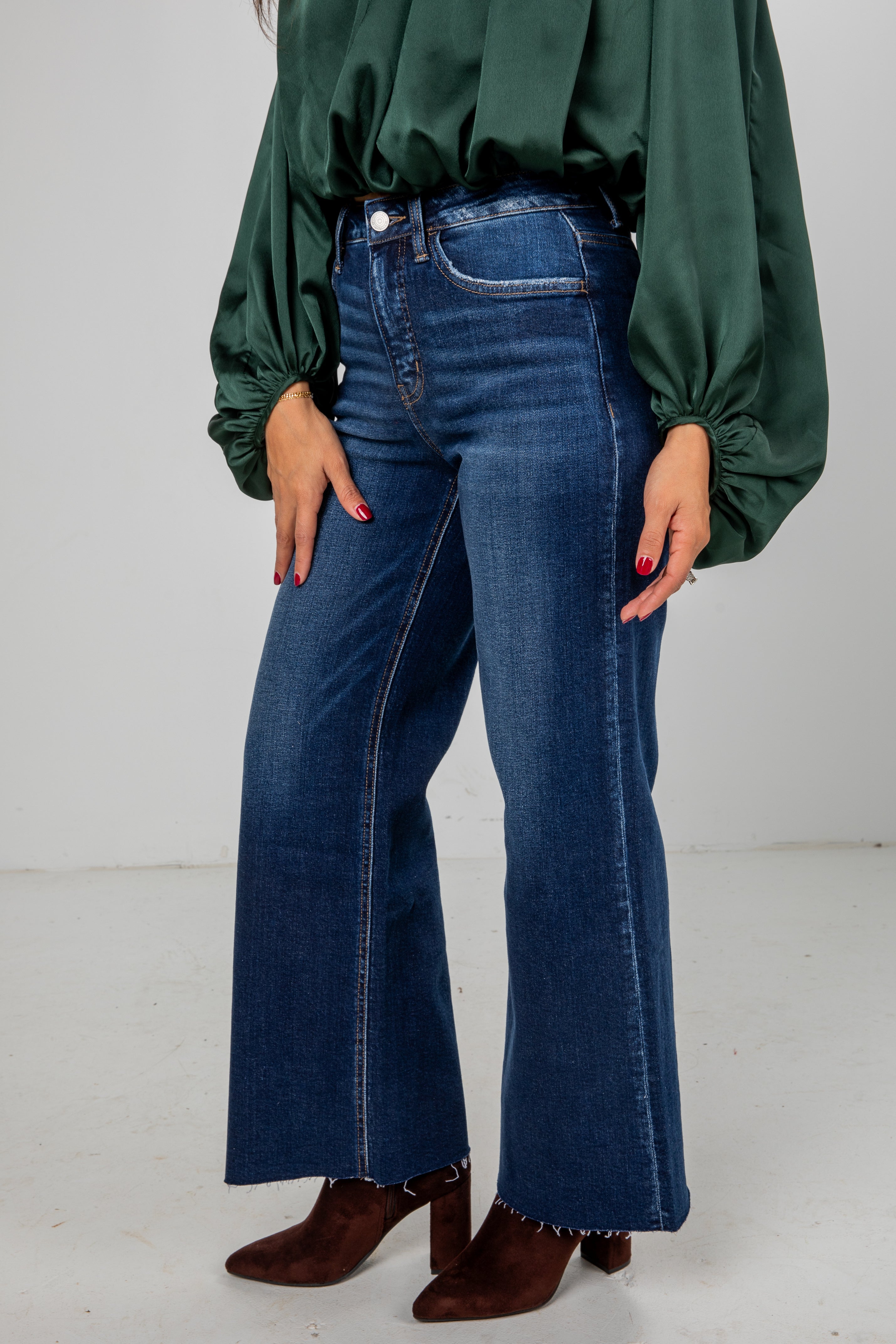 Person wearing blue jeans and a green blouse on a white background