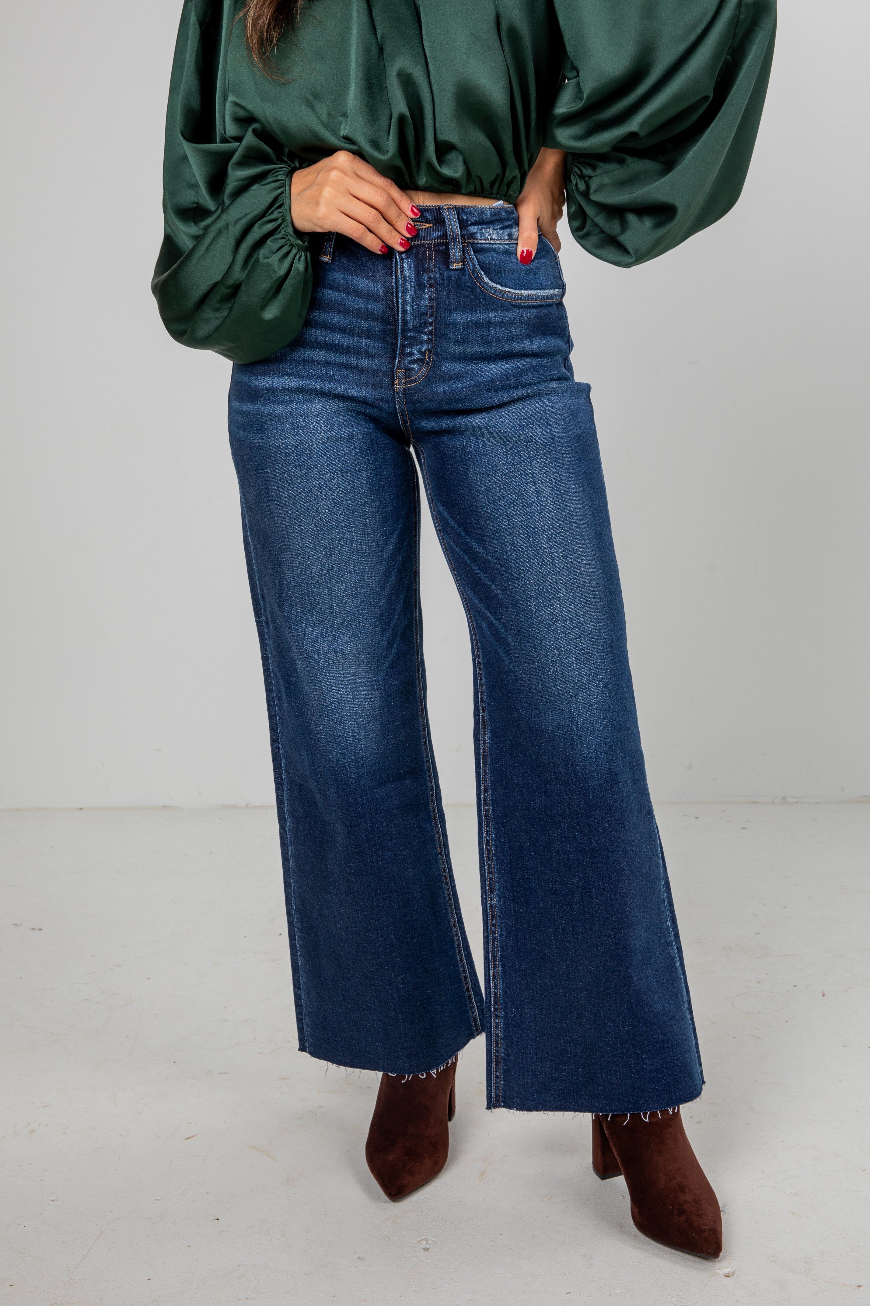 Person wearing a green blouse and blue jeans on a white background