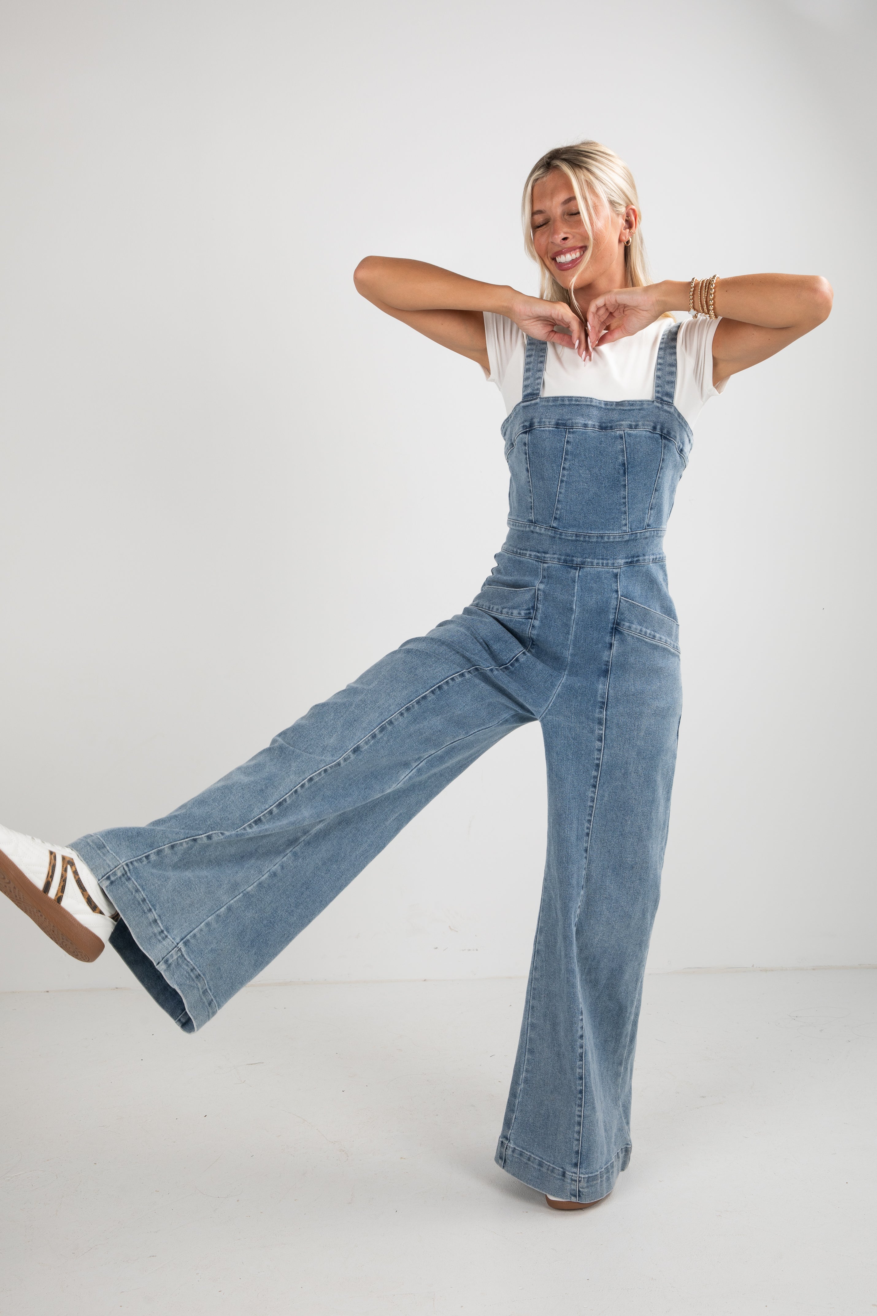 Person wearing blue denim overalls on a plain background