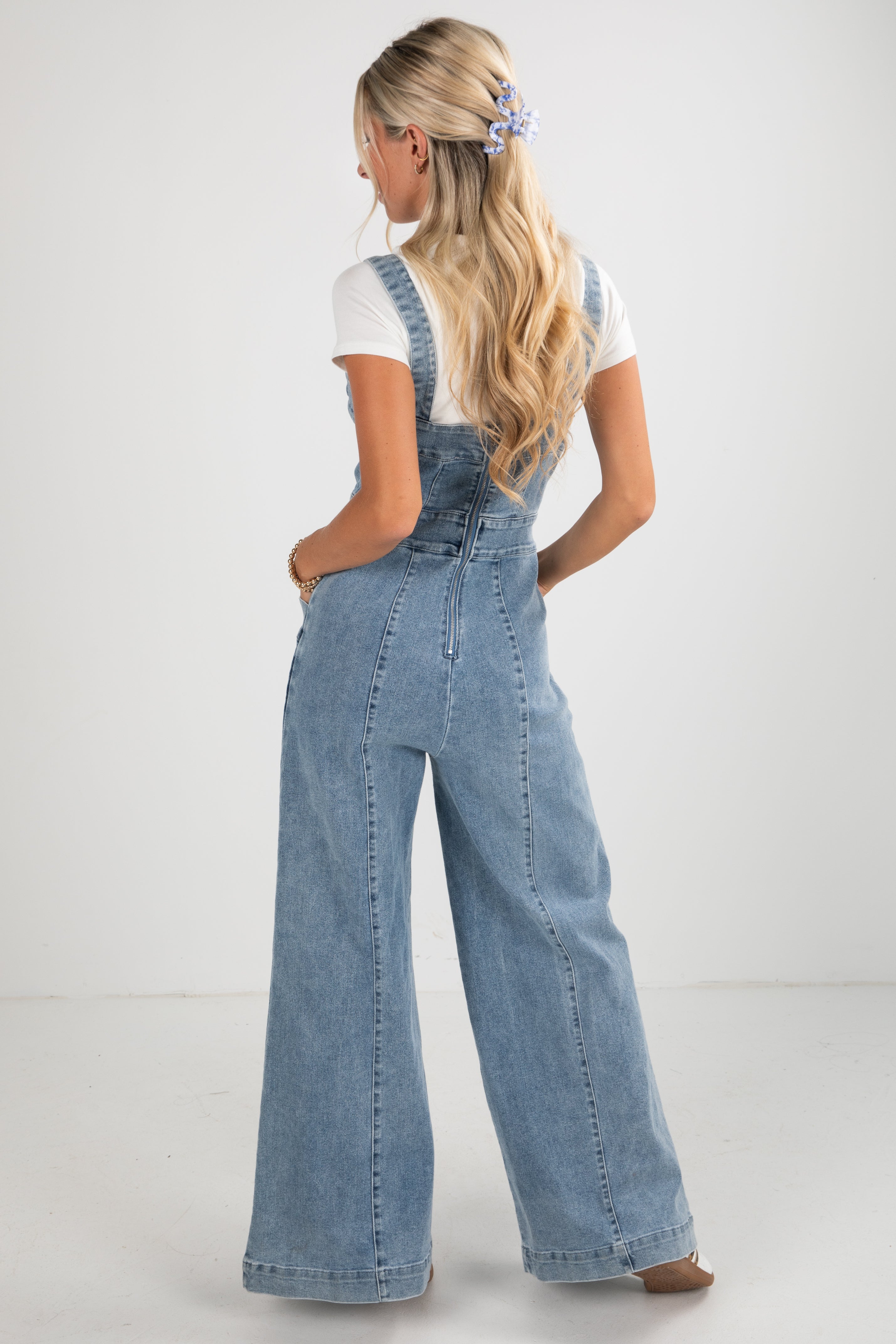 Woman wearing denim overalls on a plain background