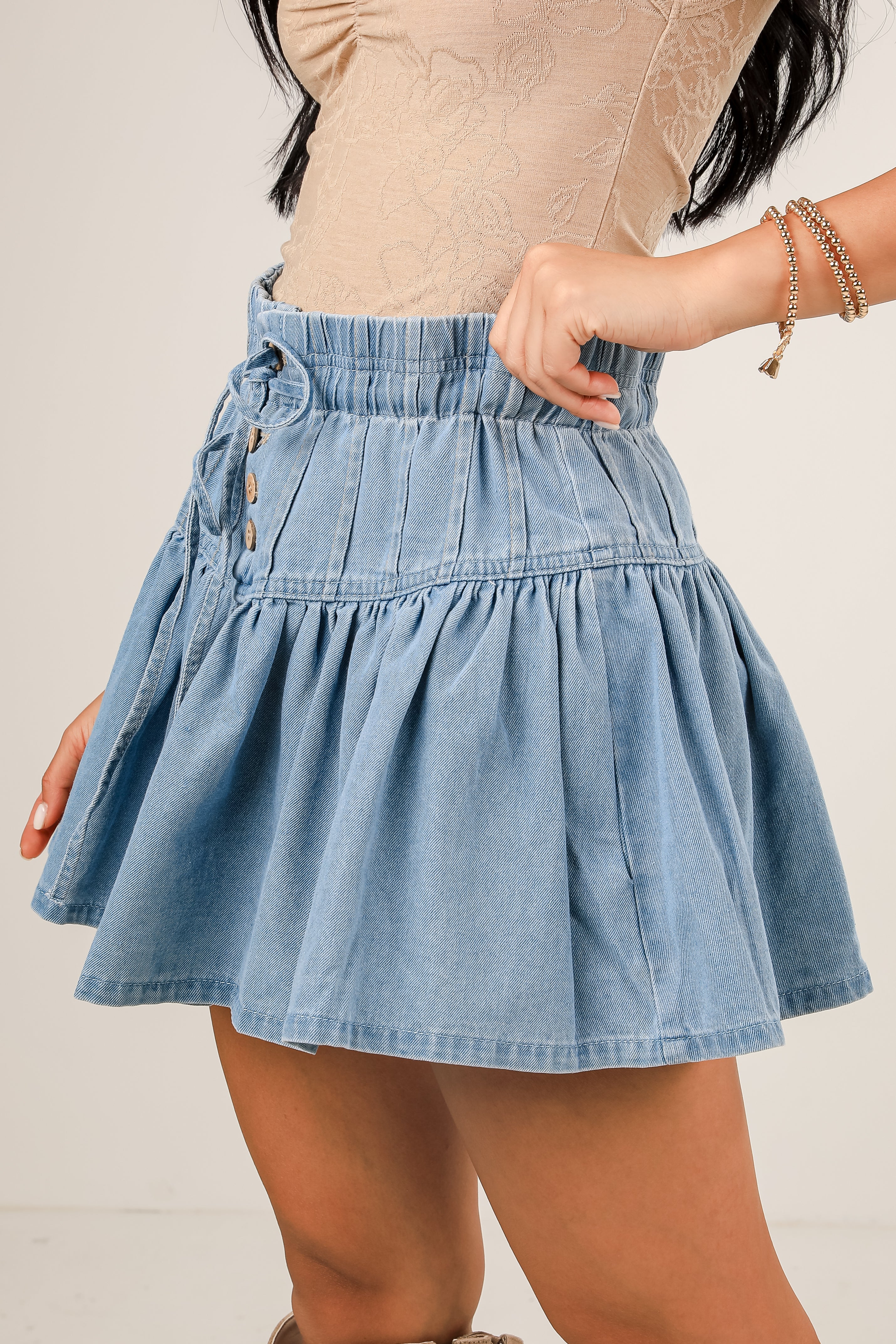 Denim skirt worn by a person on a plain background