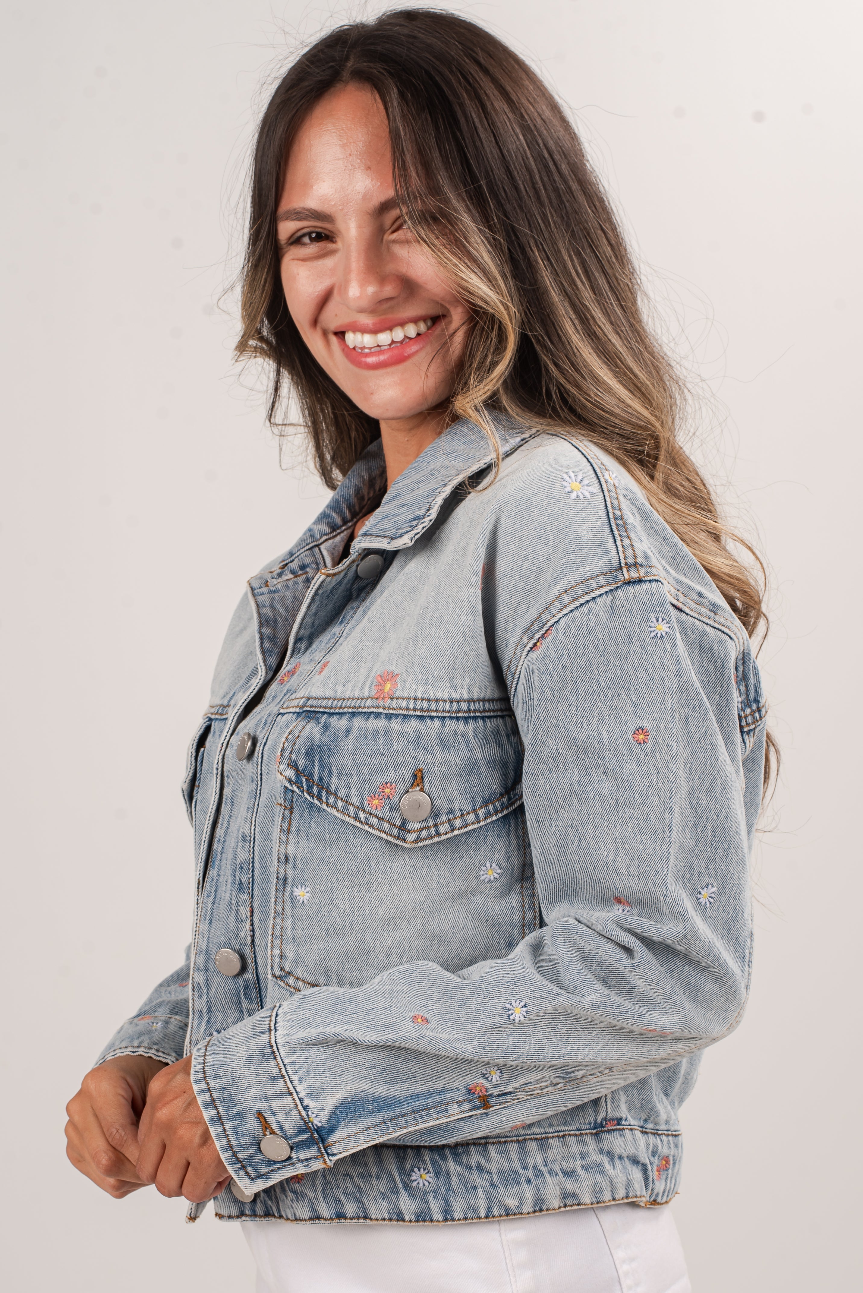 Woman wearing a light blue denim jacket with subtle distressing on a plain background