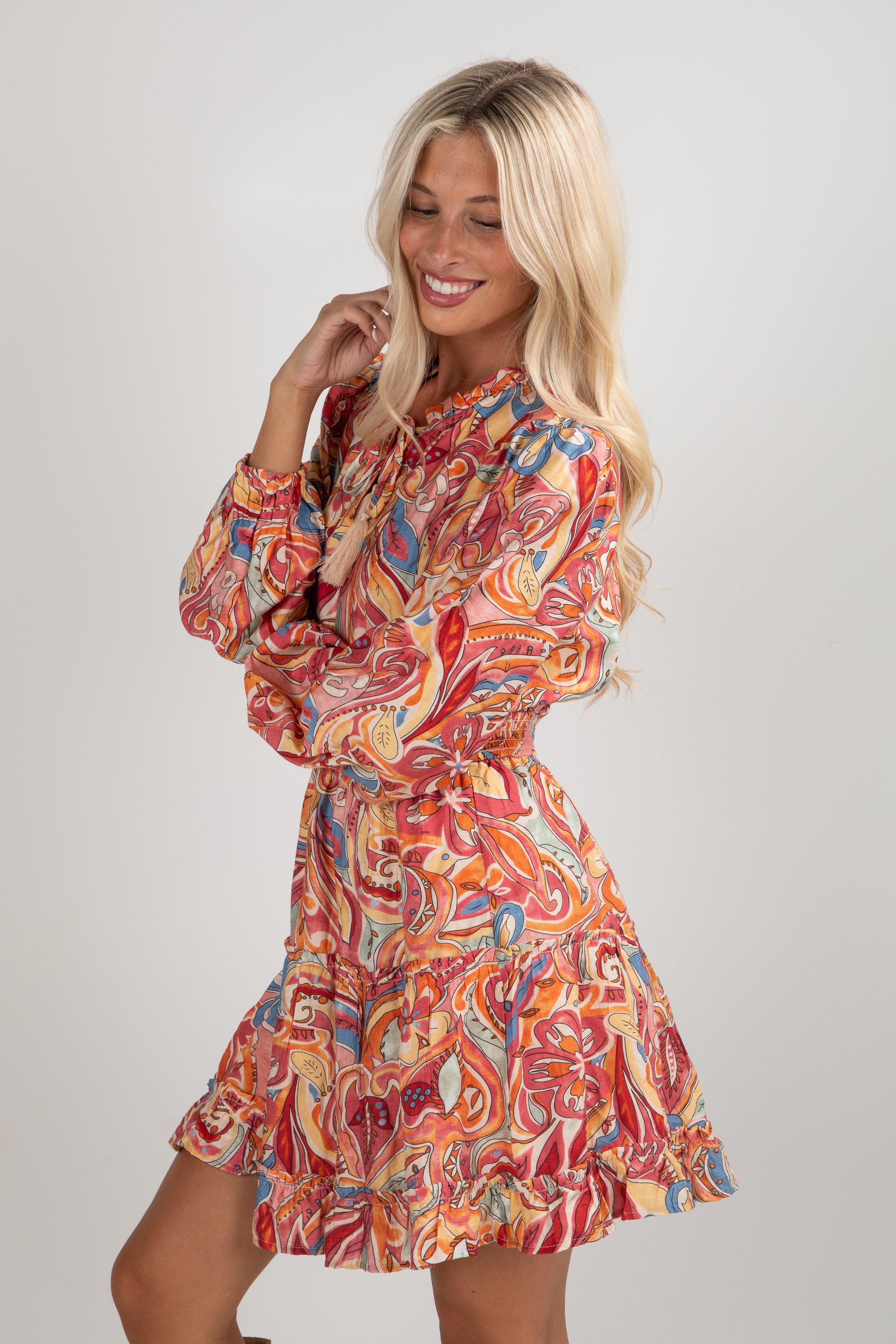 Woman wearing a colorful patterned dress on a plain background