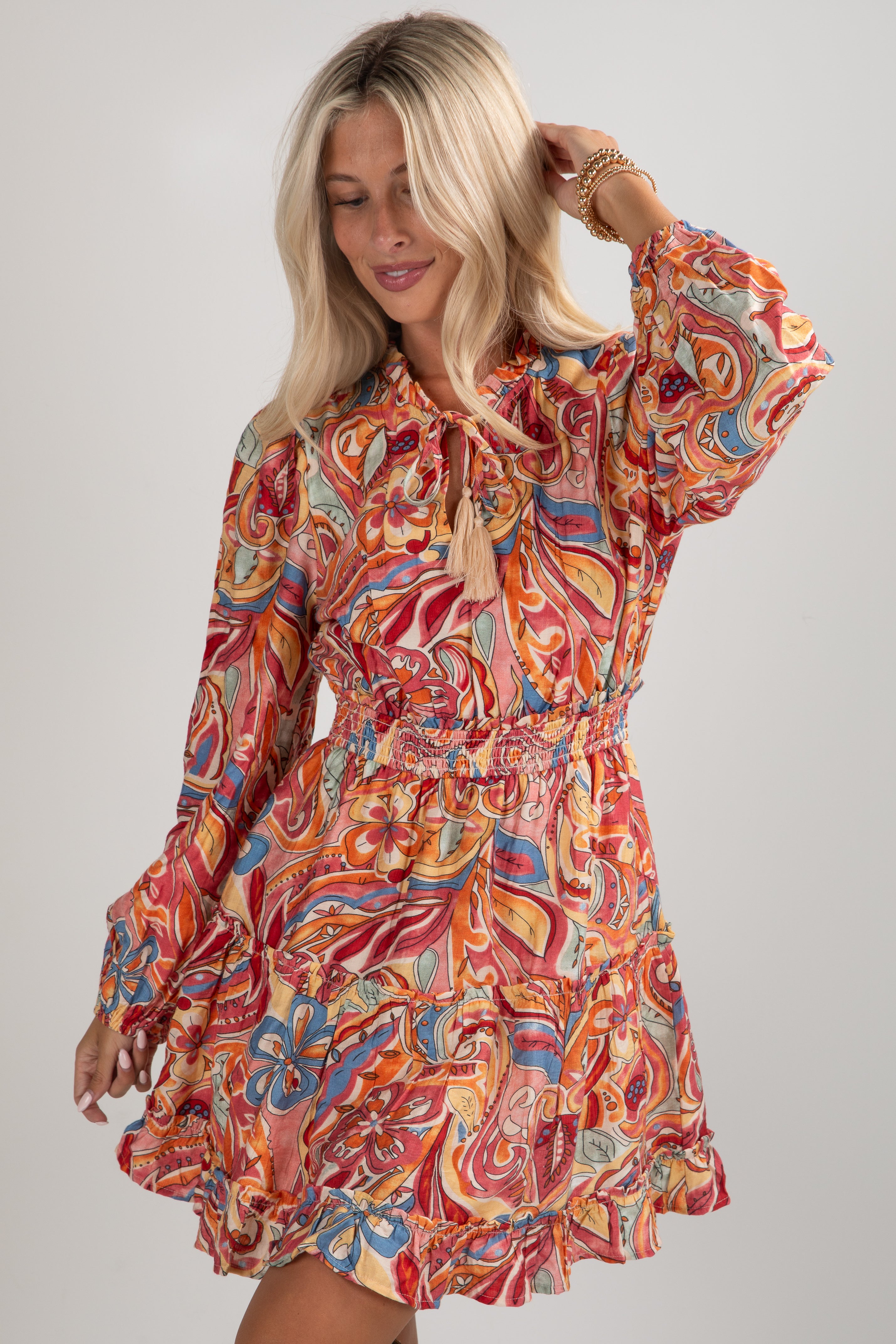 Woman wearing a colorful patterned dress on a plain background