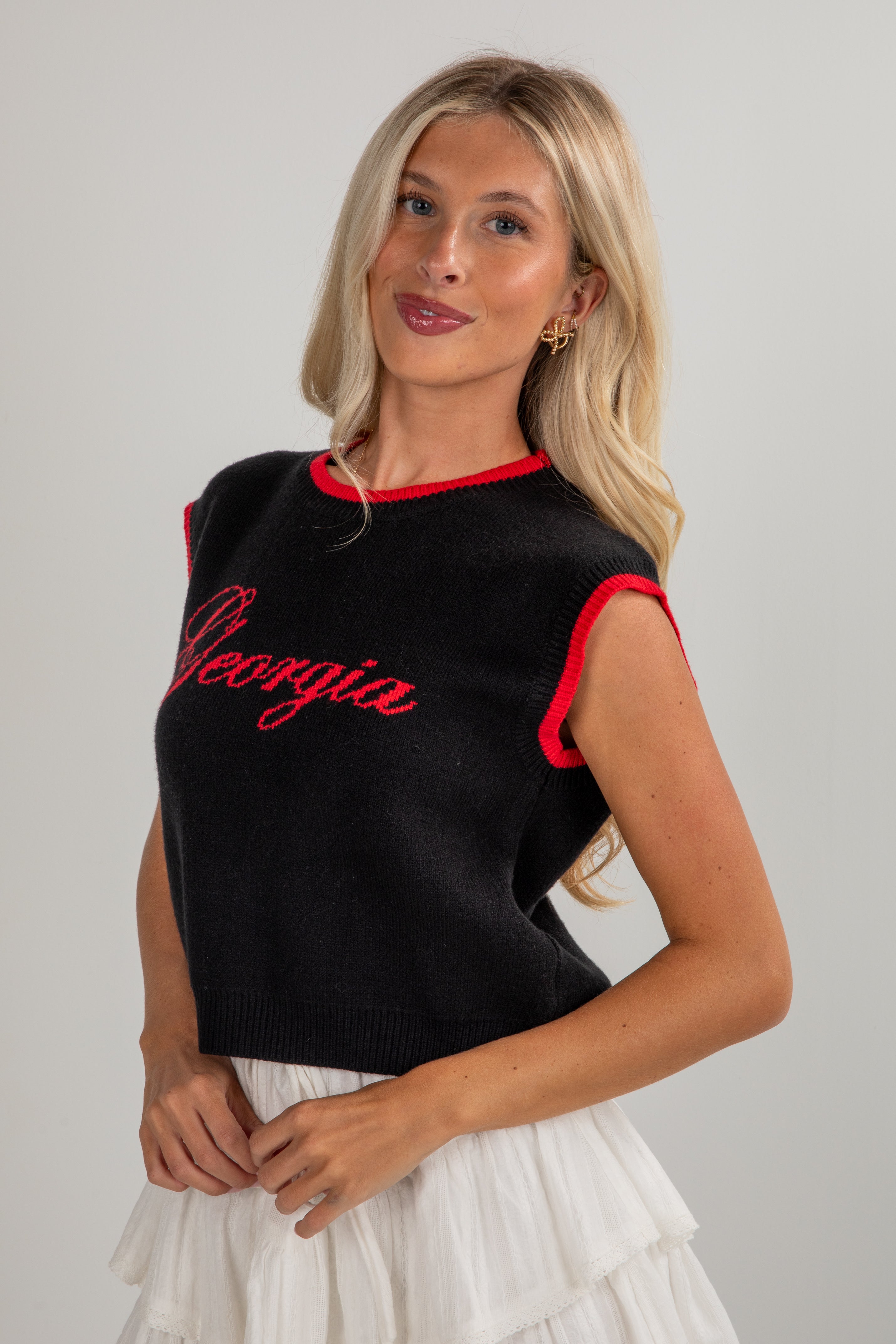 Woman wearing a black sleeveless top with red trim and &