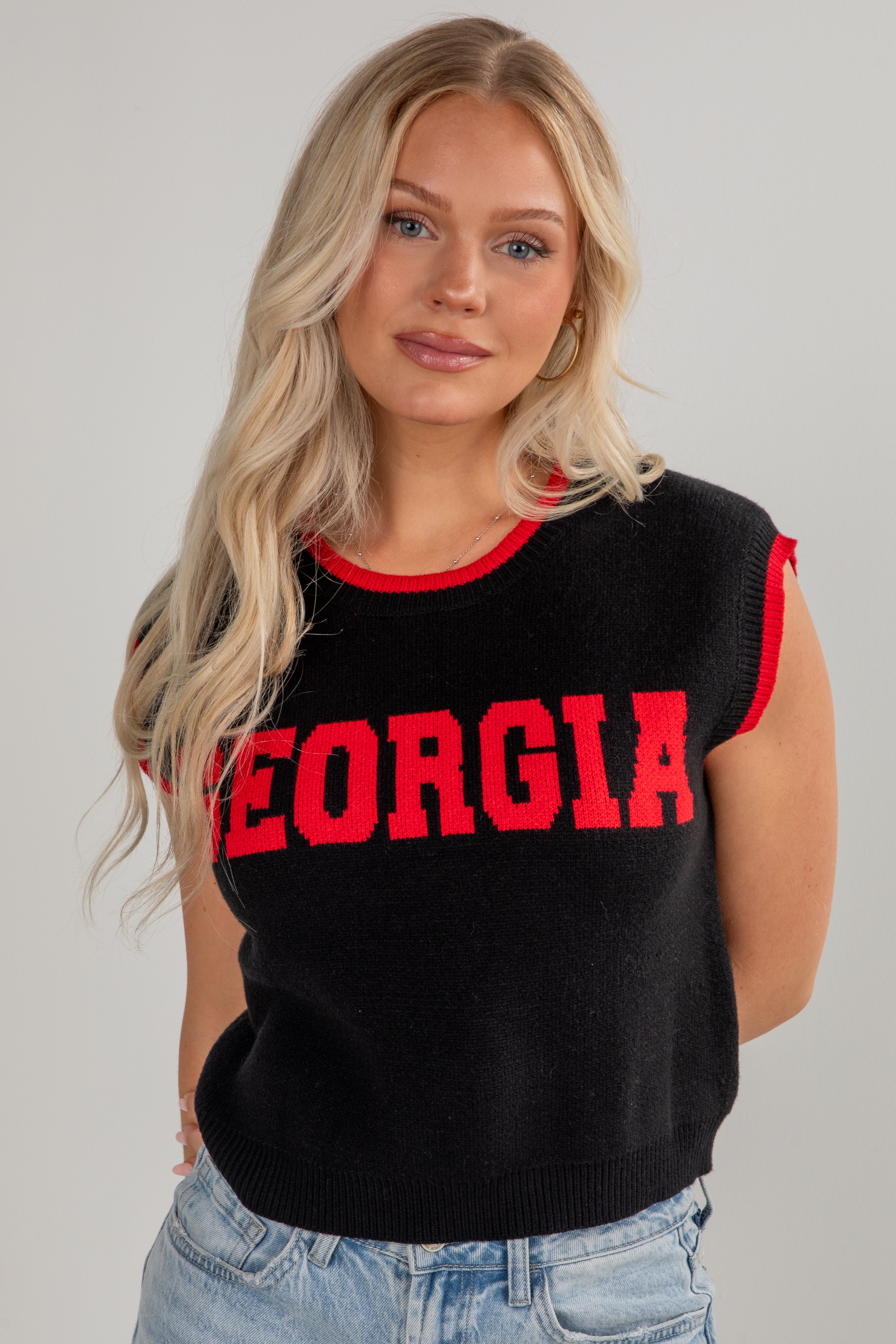 Woman wearing a black sleeveless sweater with &