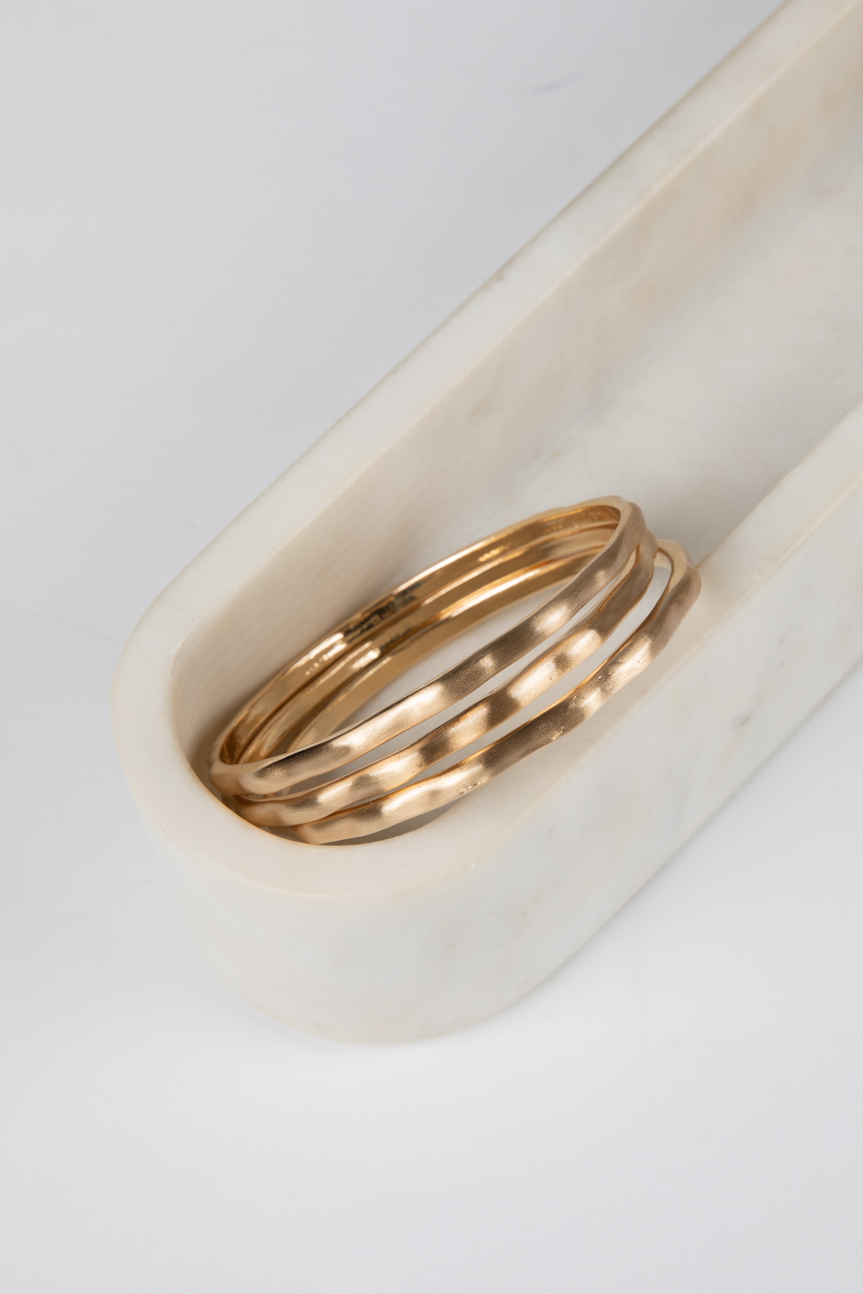 Two gold rings on a white marble surface