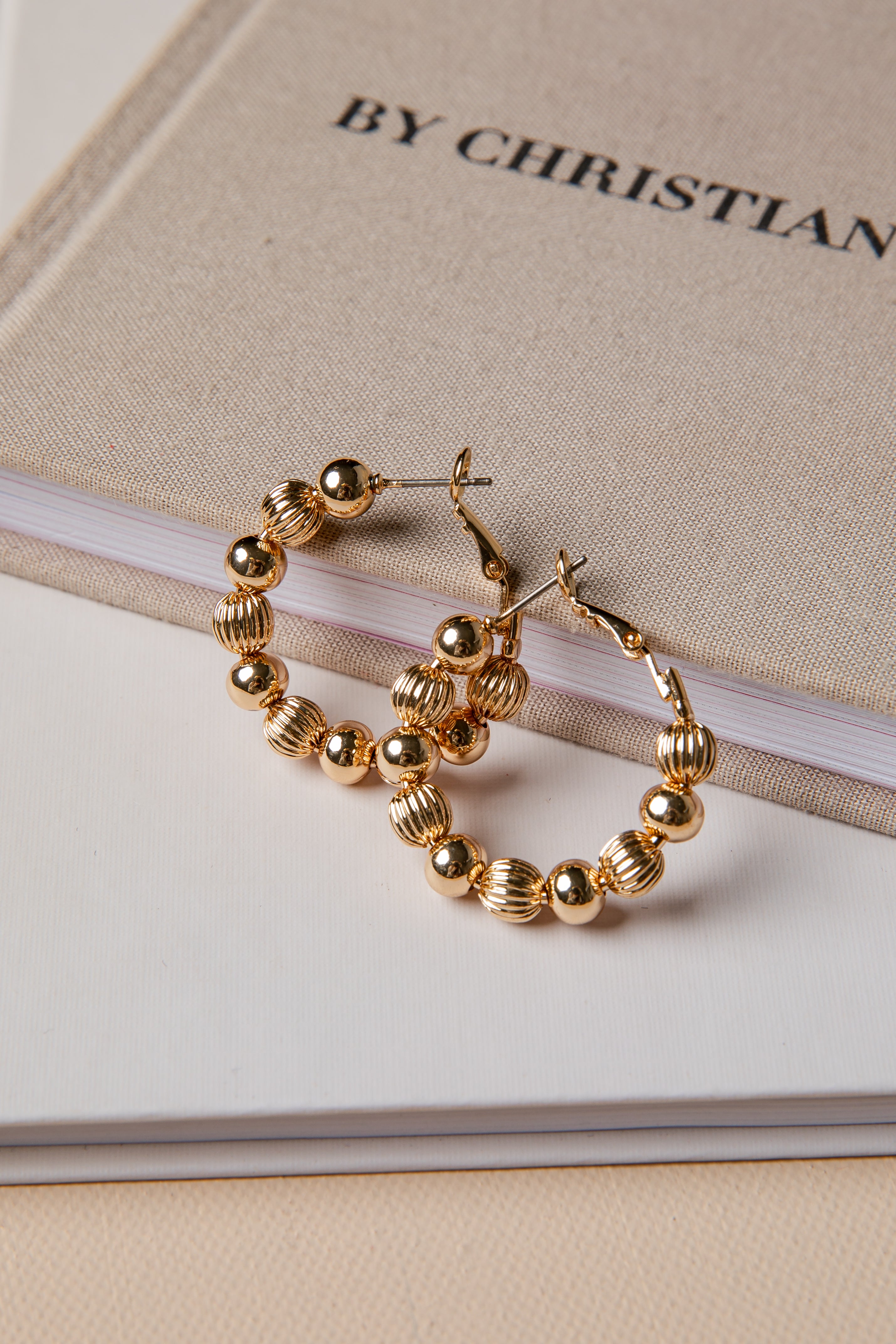 Gold hoop earrings on a book with &
