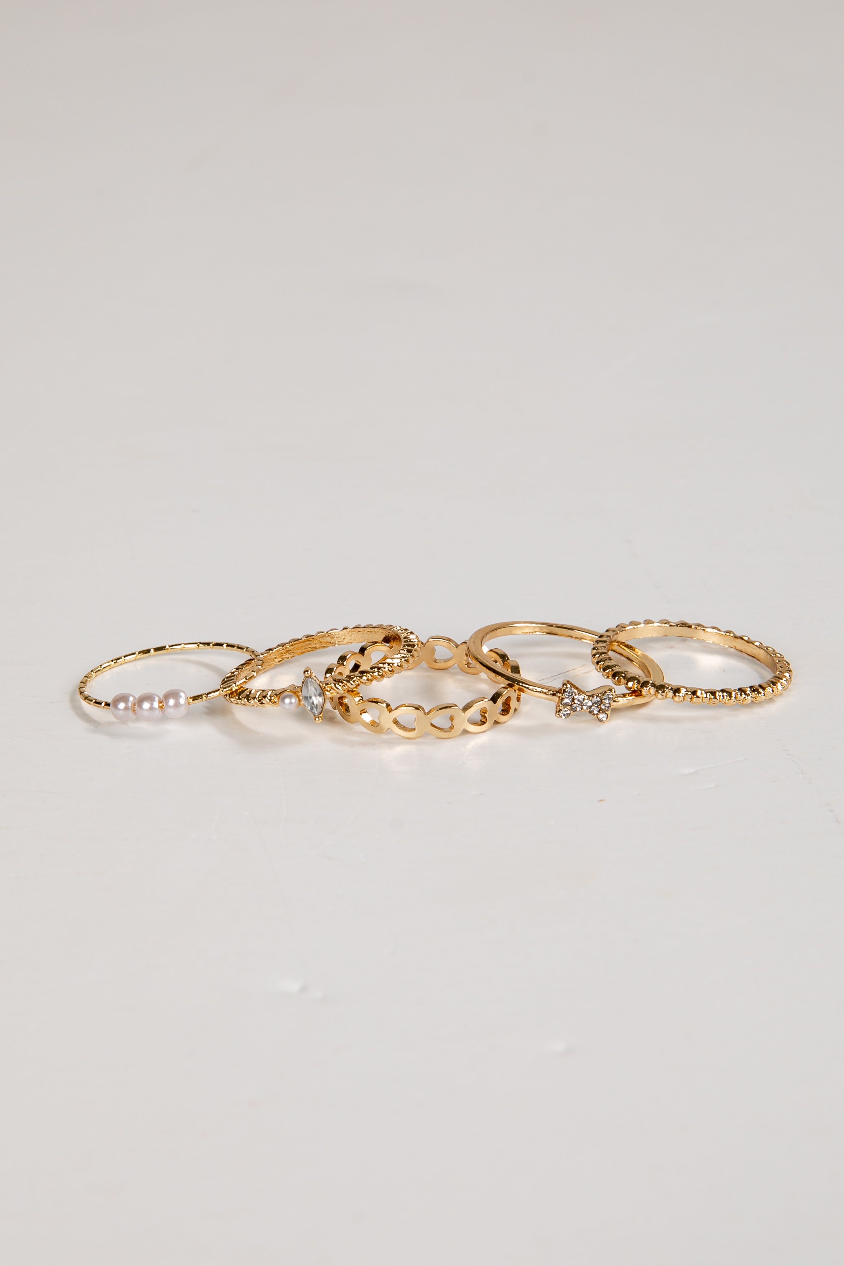 Set of gold rings with small stones on a light gray background