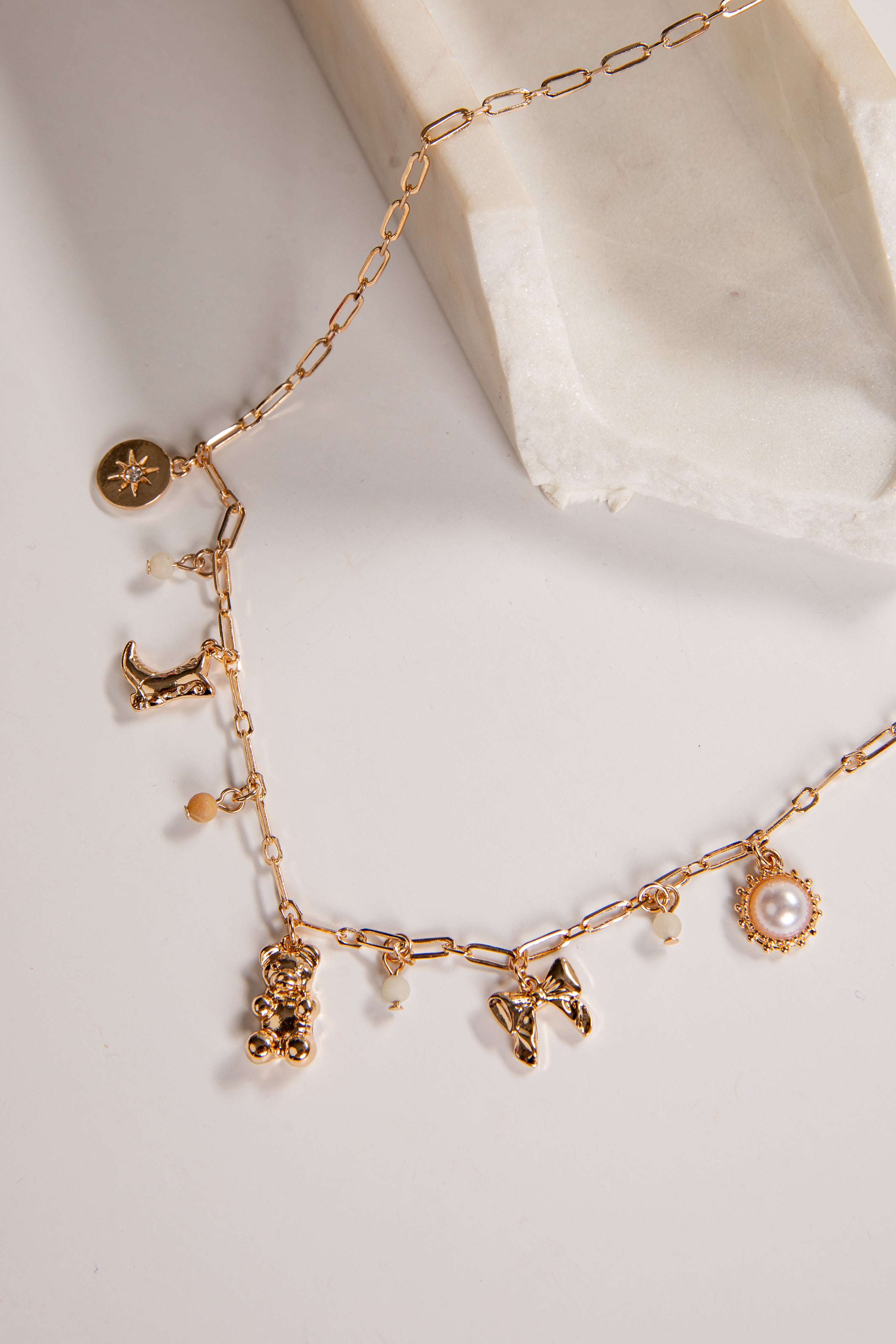 Gold necklace with various charms on a light background