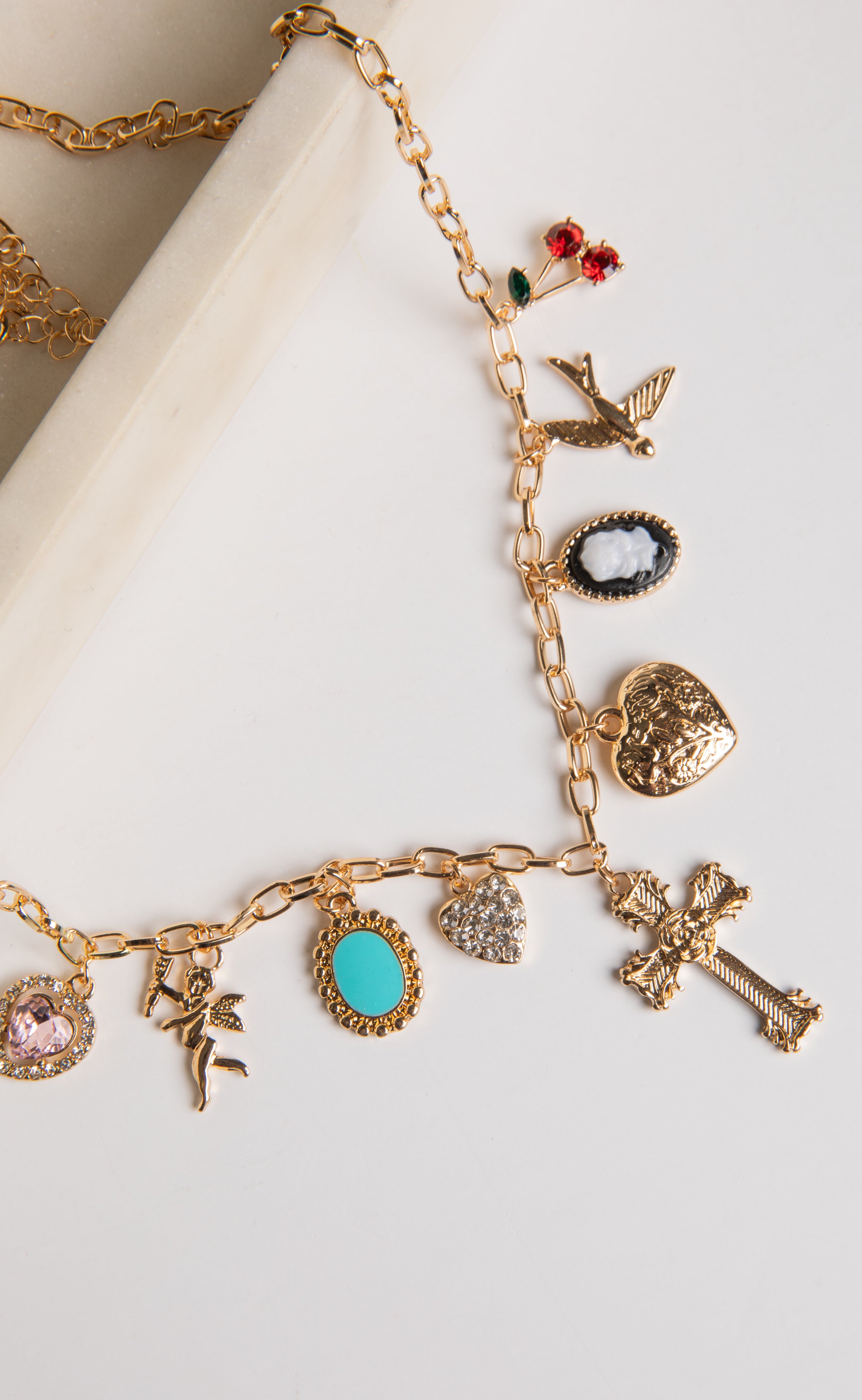 Gold charm bracelet with various charms on a white surface