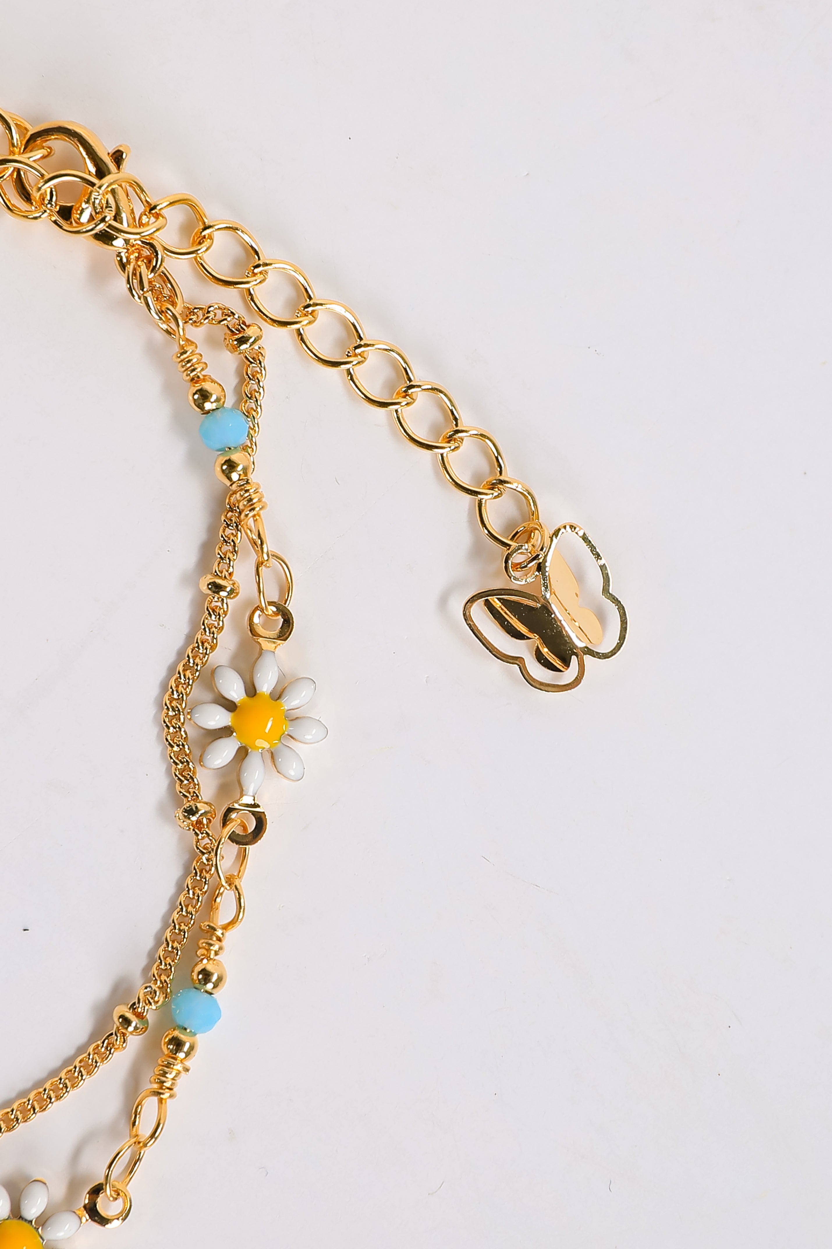 Gold bracelet with floral charms on a light gray background