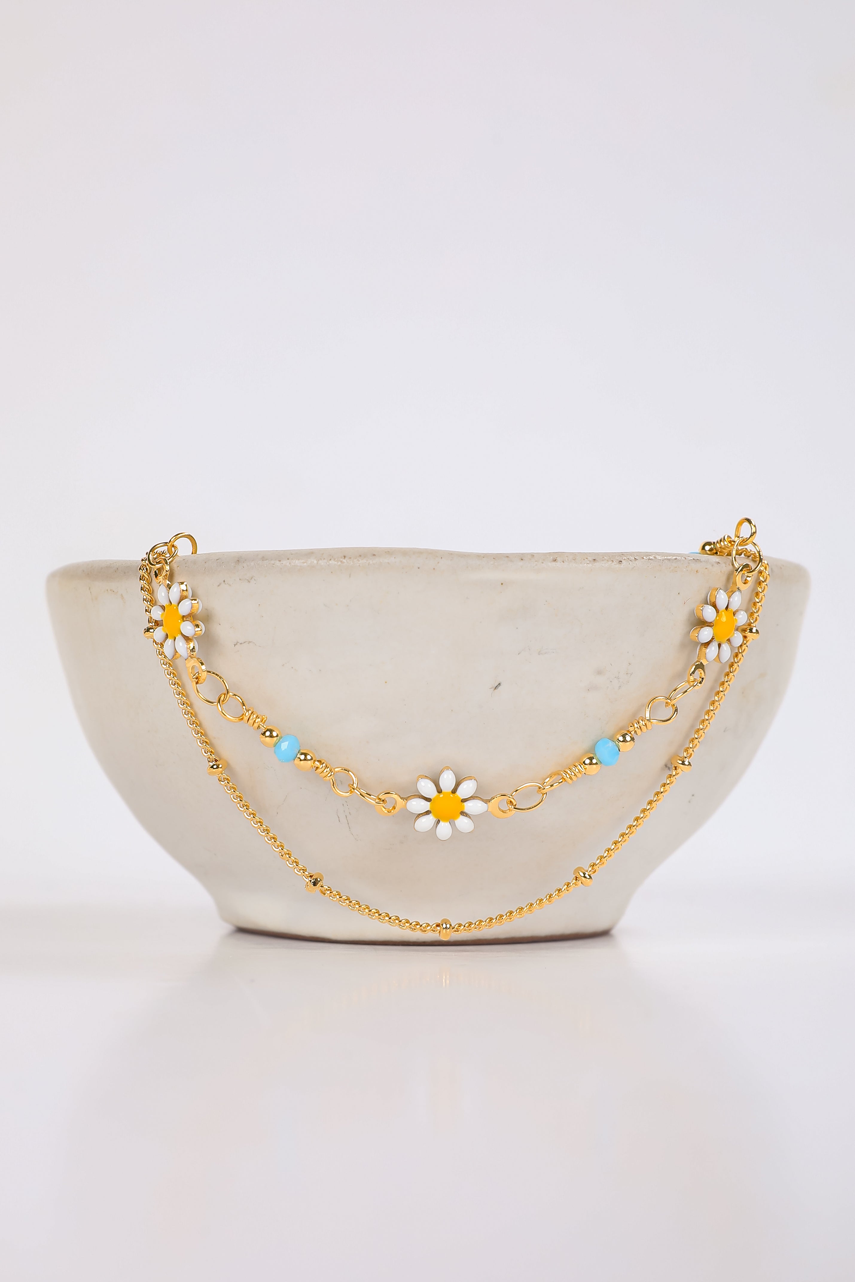 Gold chain necklace with floral pendants on a white background