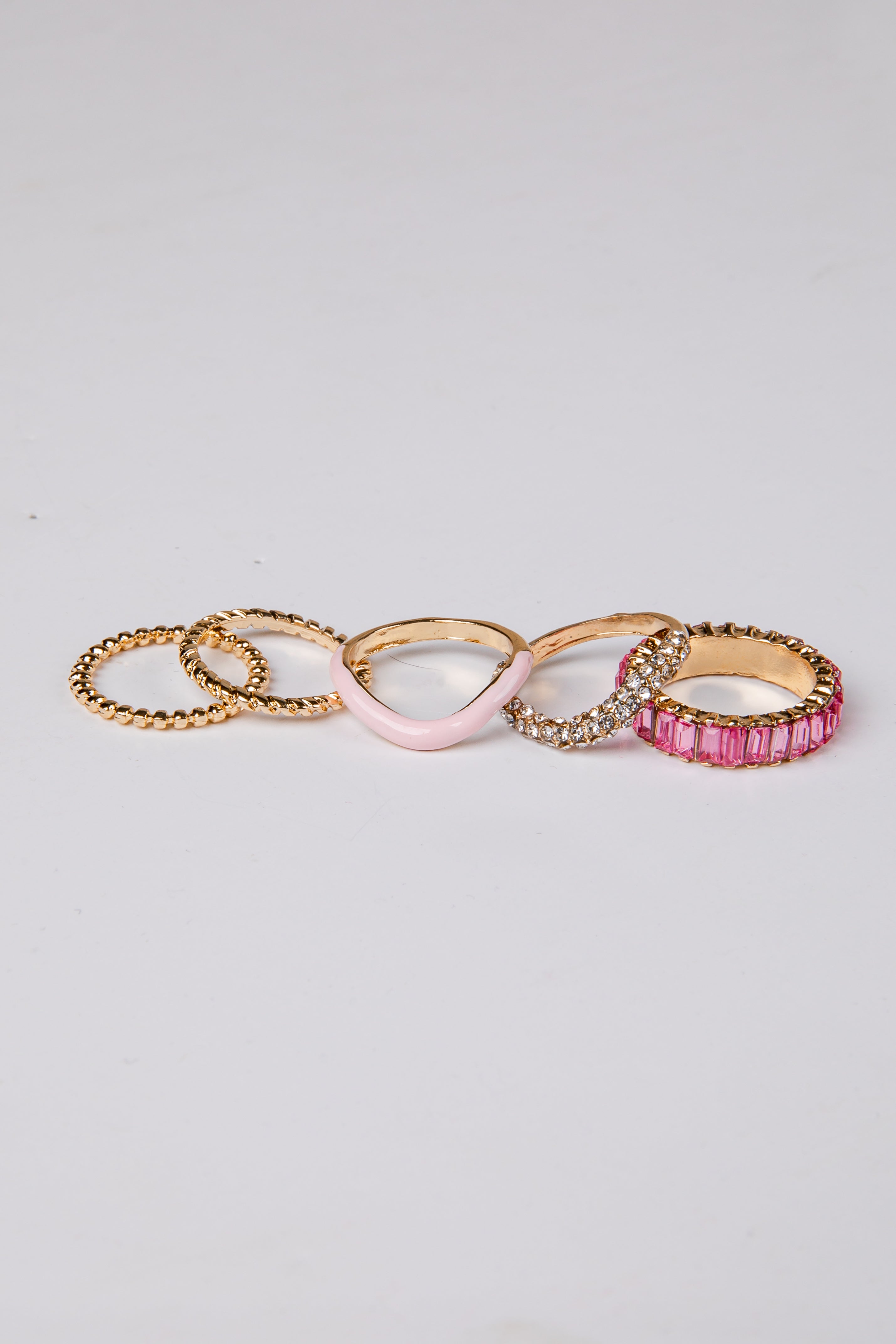Set of five gold and pink rings on a light gray background