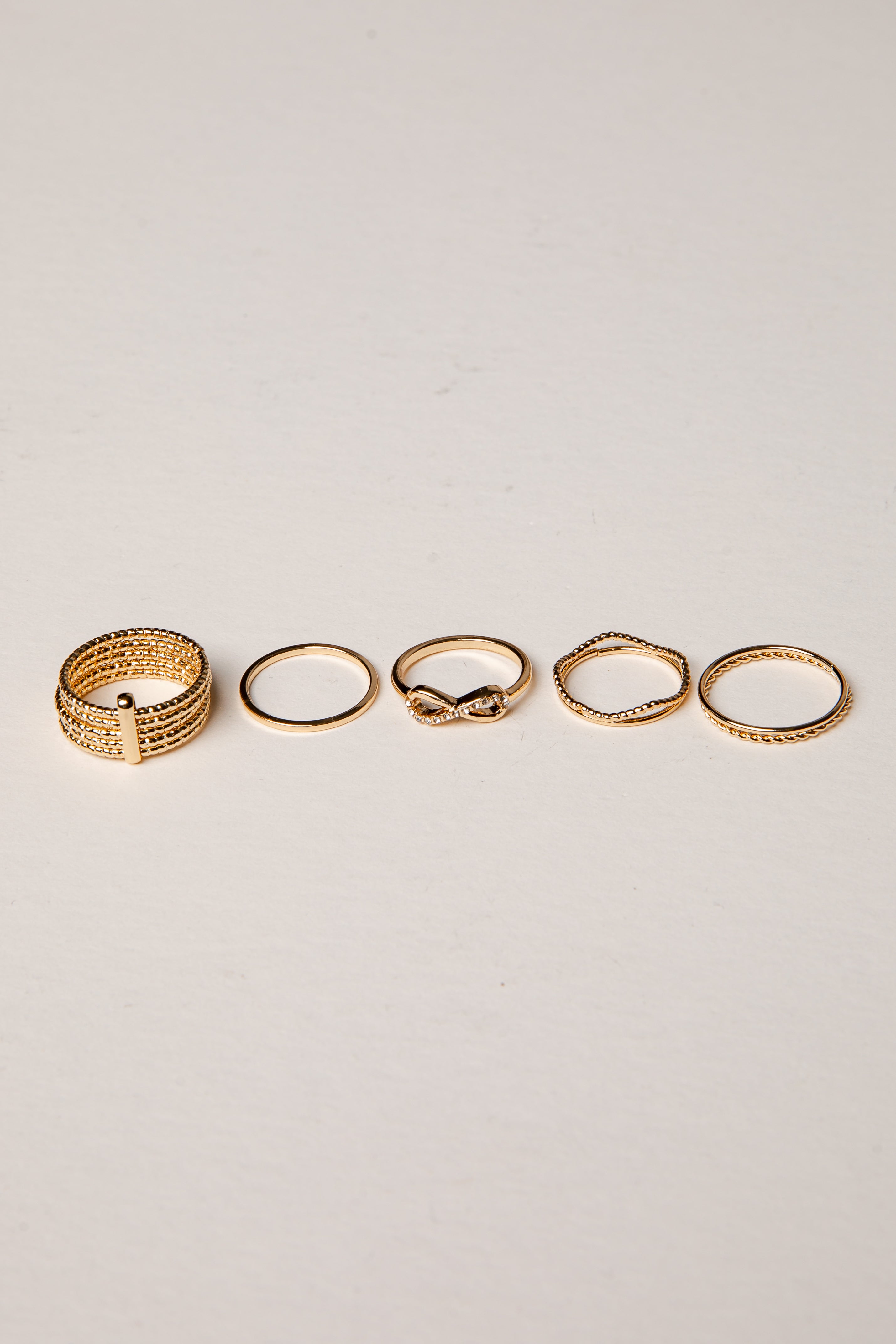 Set of five gold rings on a light gray background
