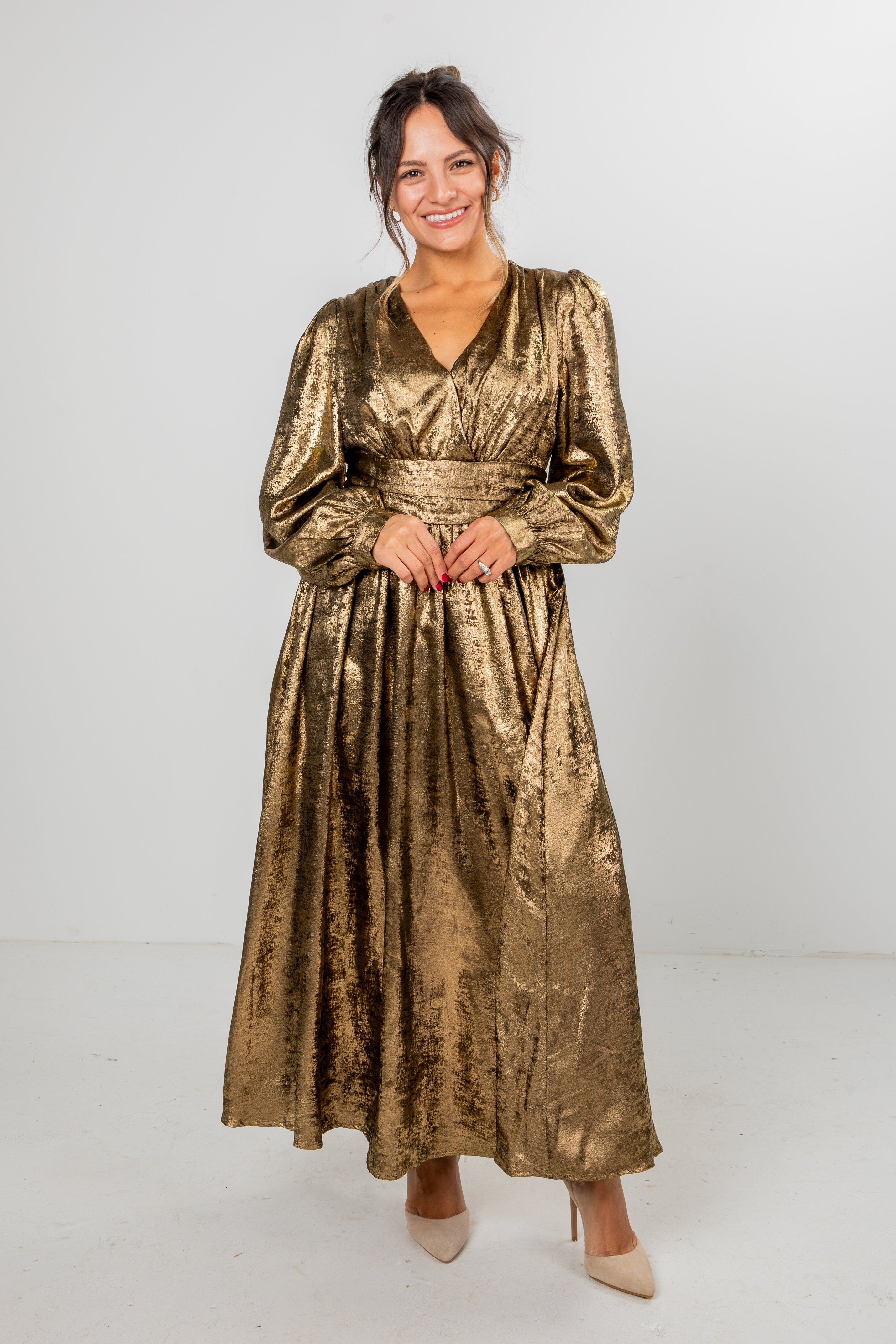 Woman wearing a gold metallic dress against a white background