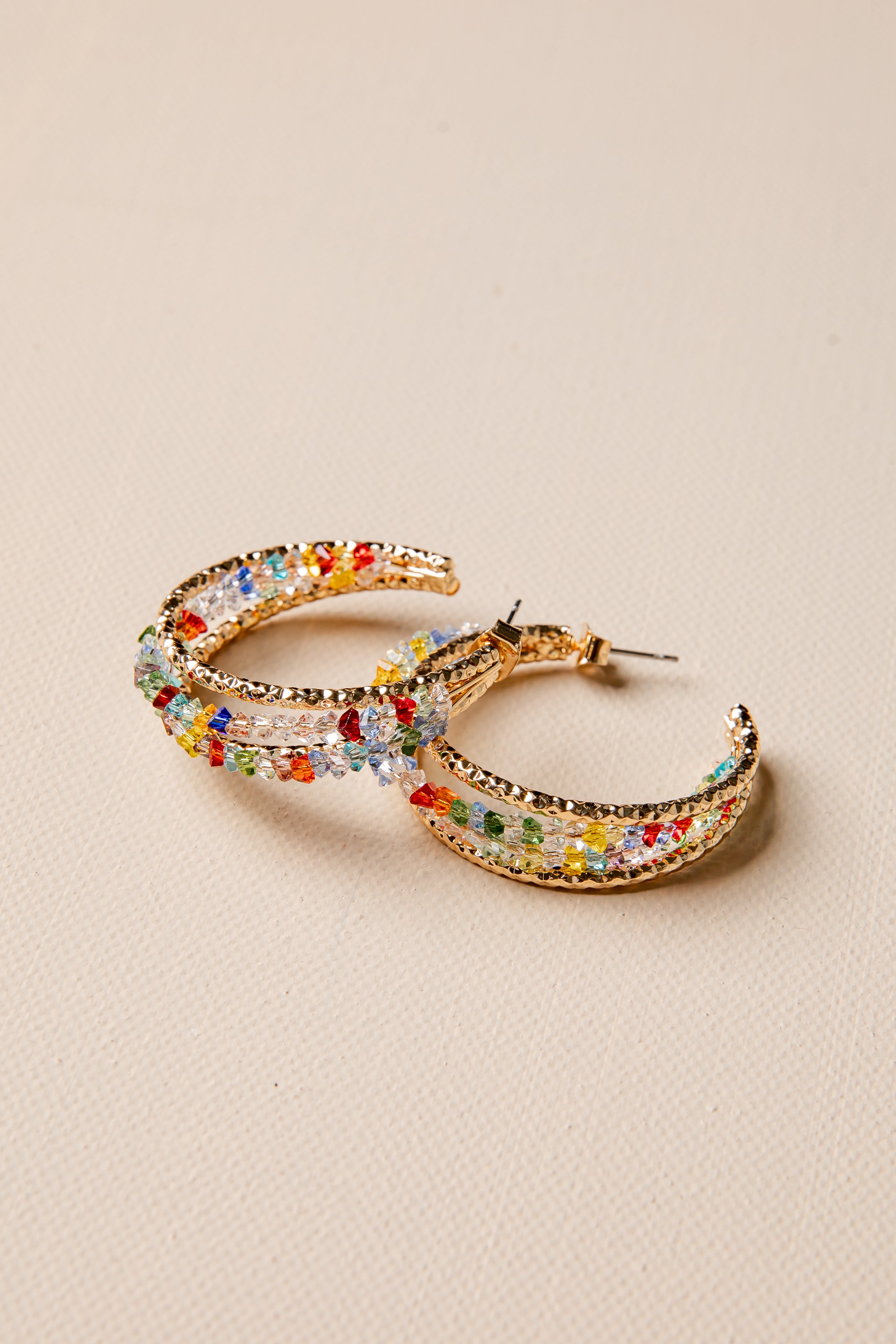 Colorful hoop earrings on a beige background