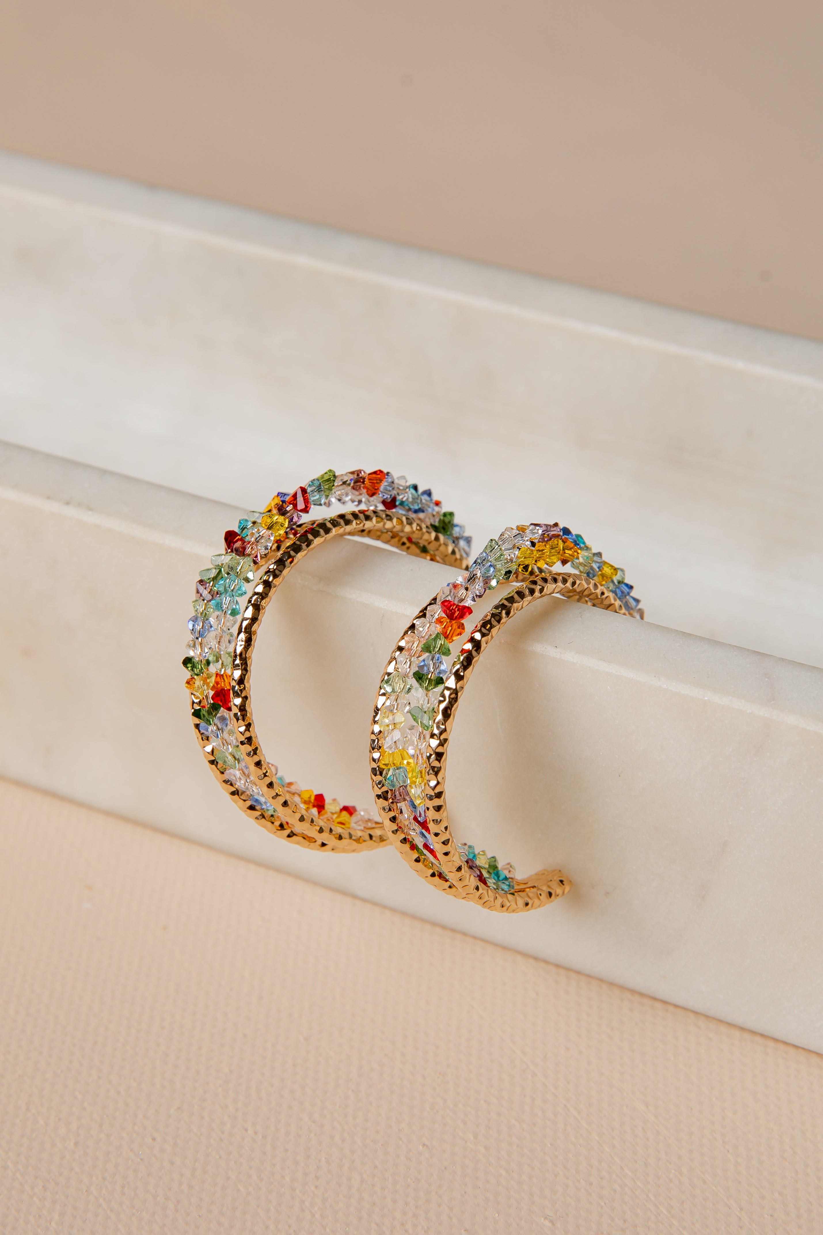 Colorful hoop earrings on a beige surface