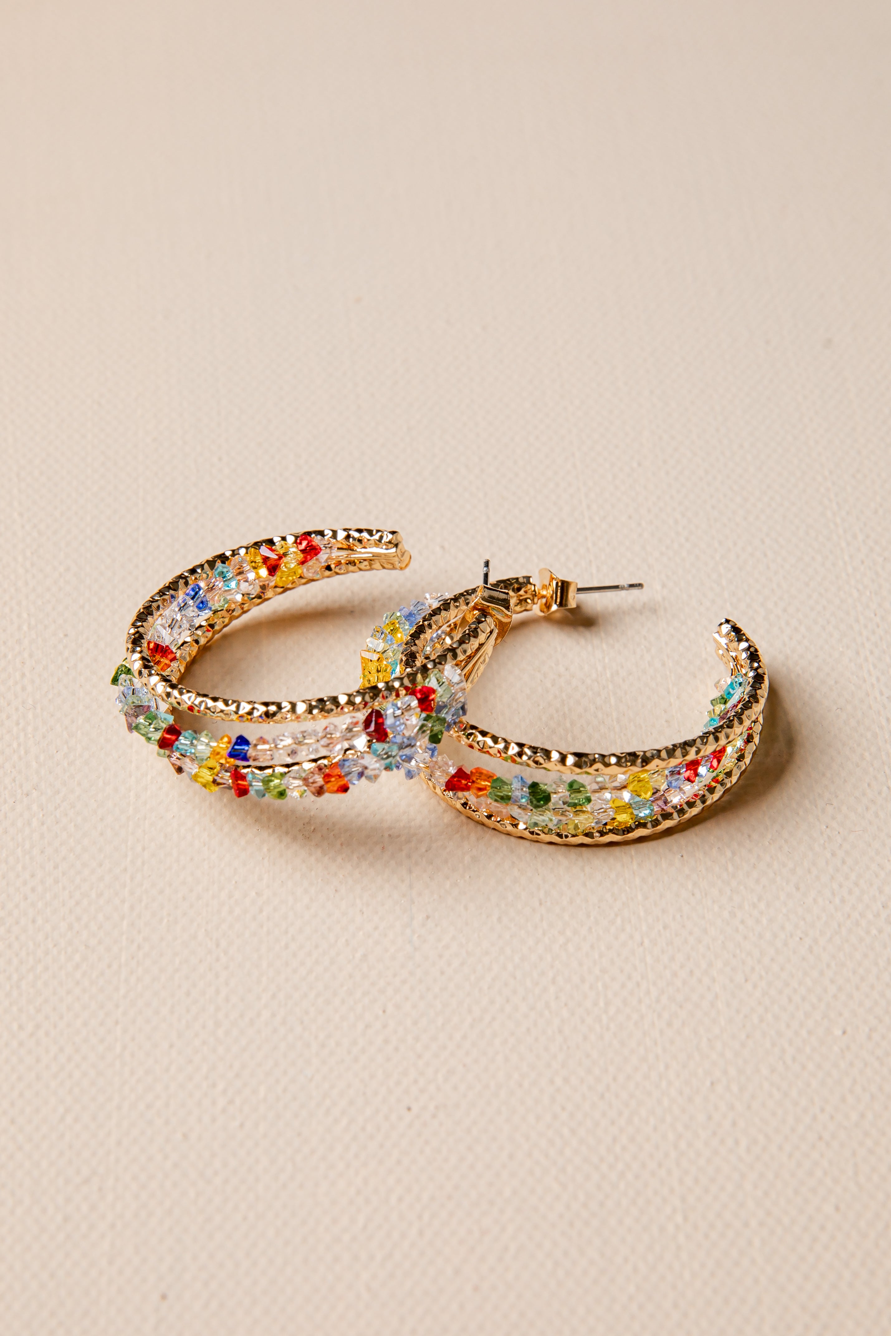 Colorful hoop earrings on a beige background