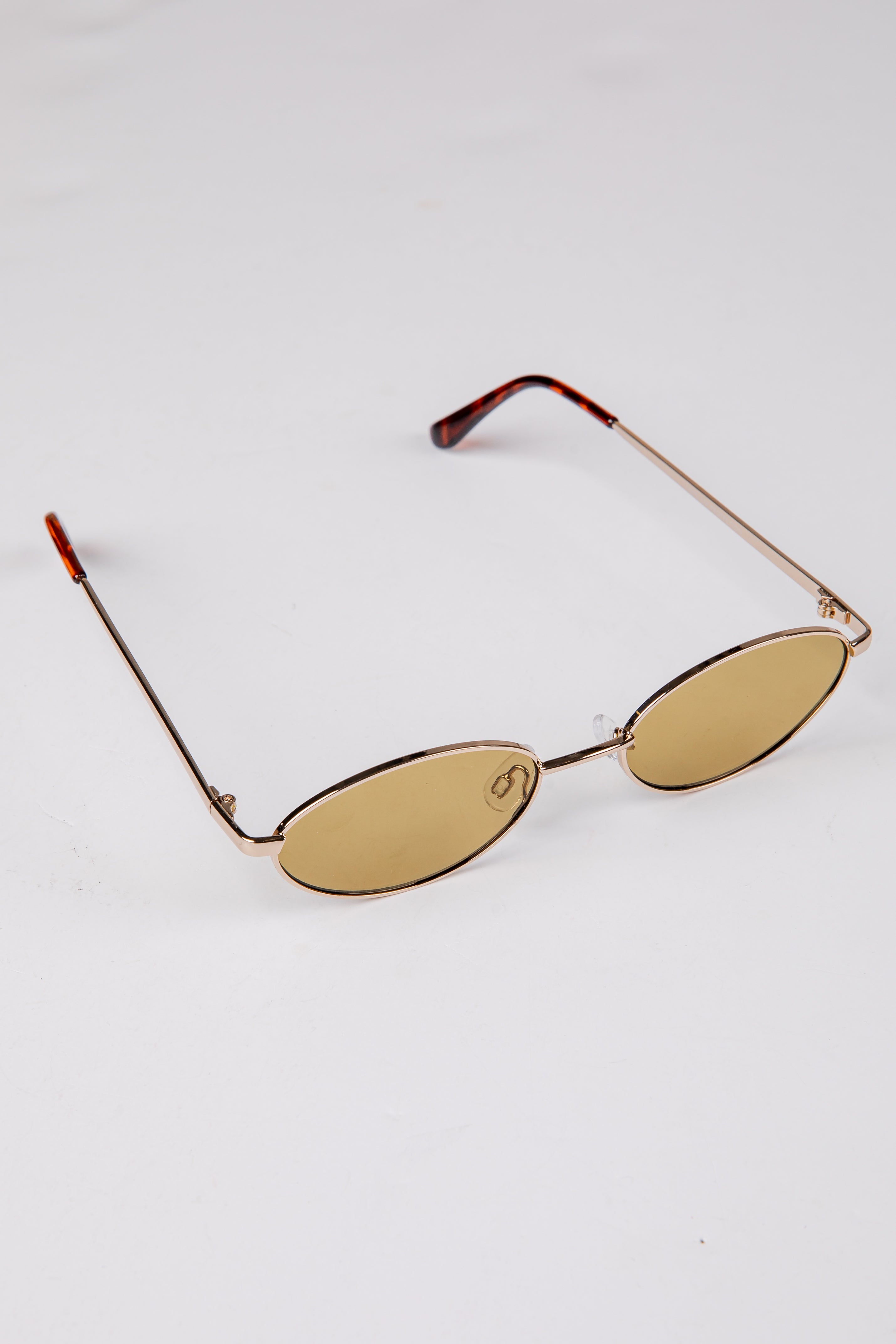 Gold-framed sunglasses with oval lenses on a white background