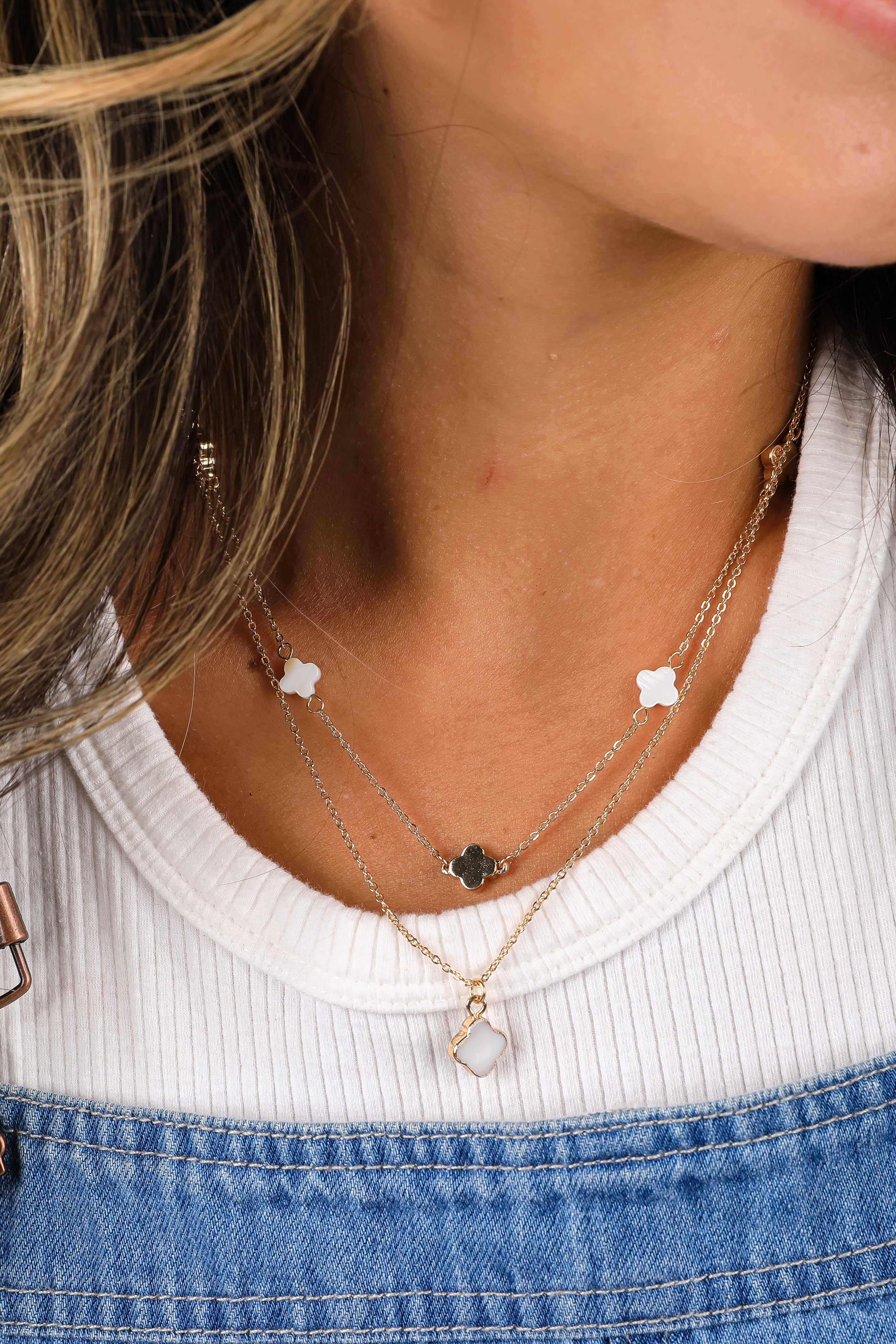 Close-up of a person wearing multiple gold necklaces with star and heart pendants.
