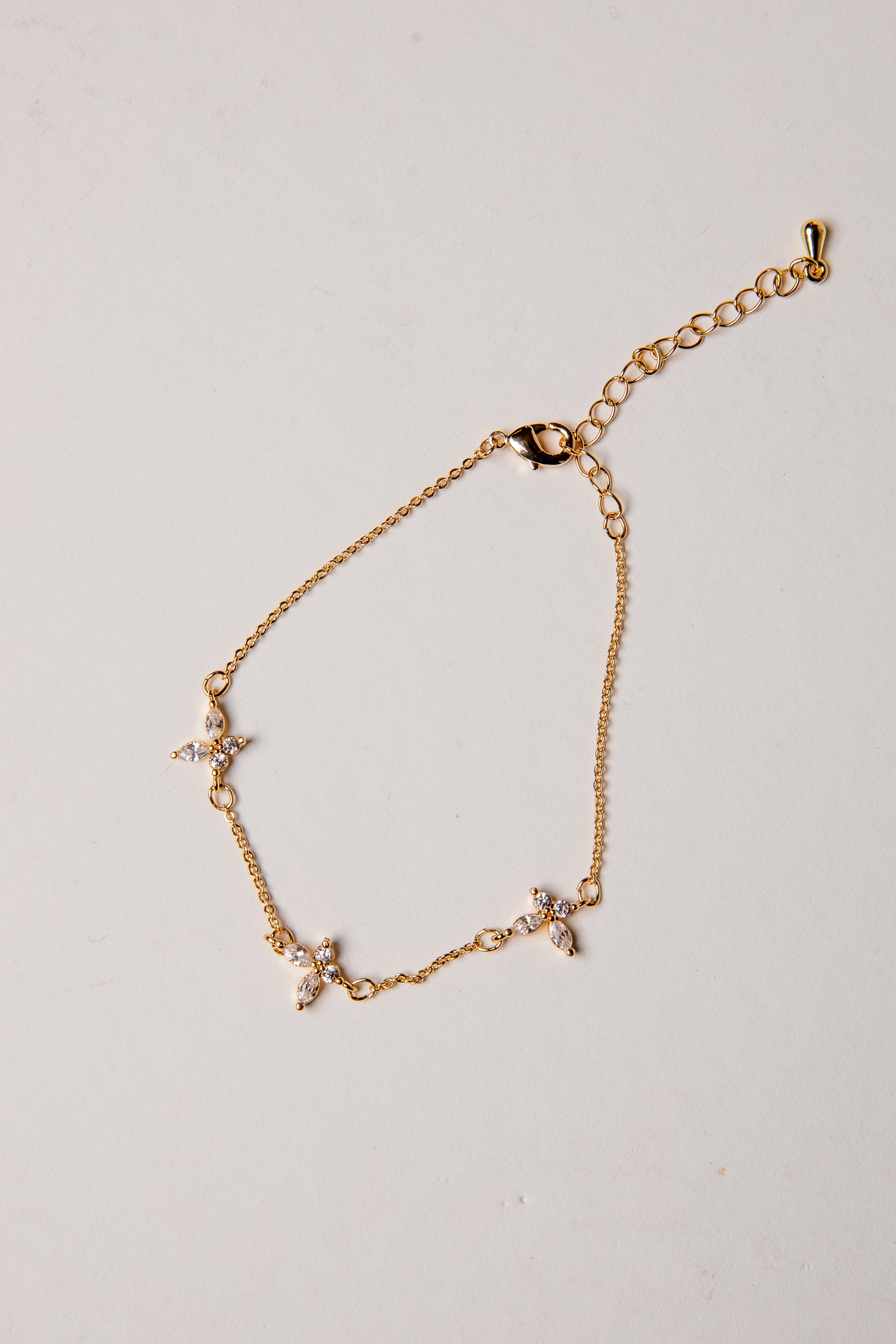 Gold bracelet with small charms on a light gray background