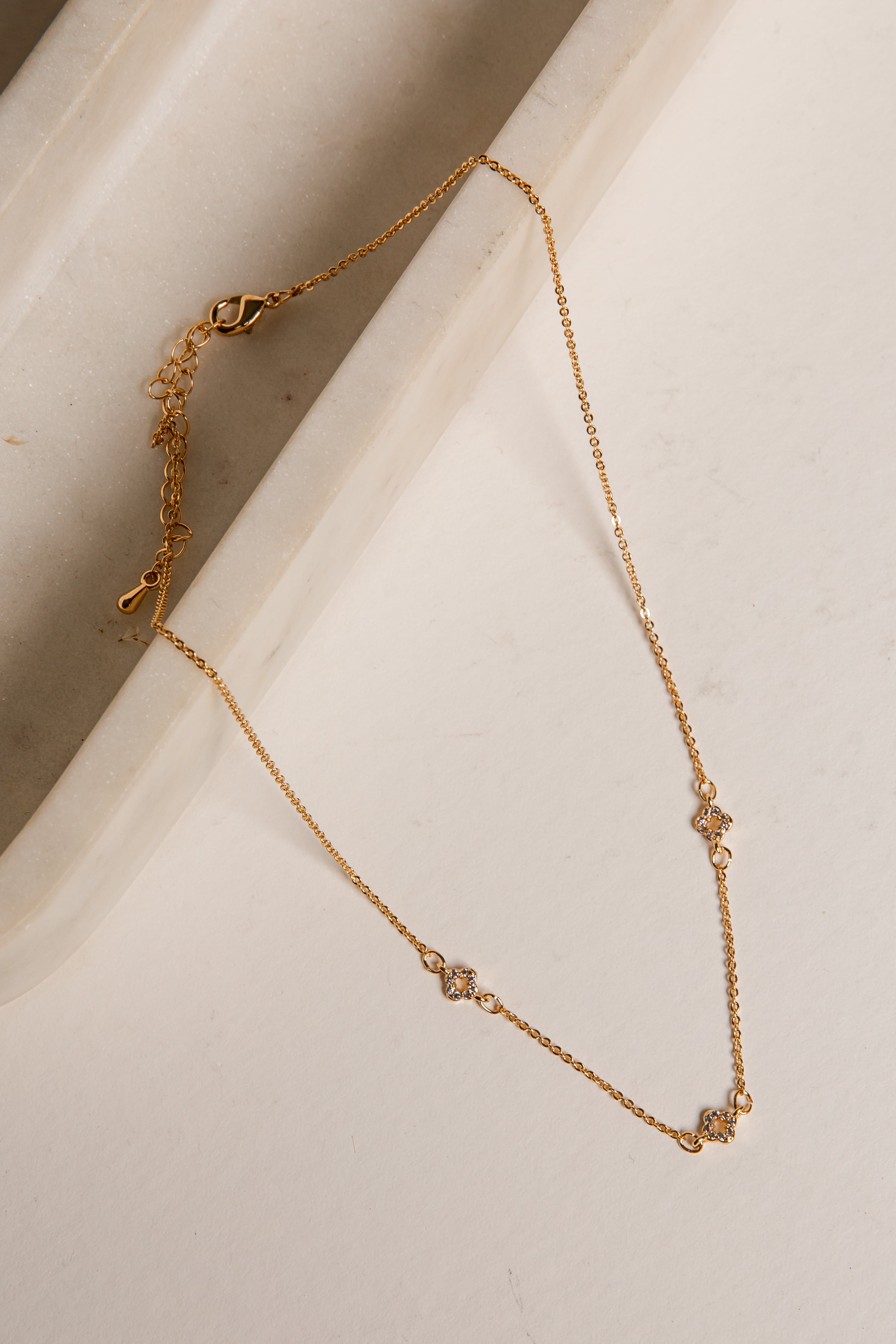 Gold necklace on a light beige surface