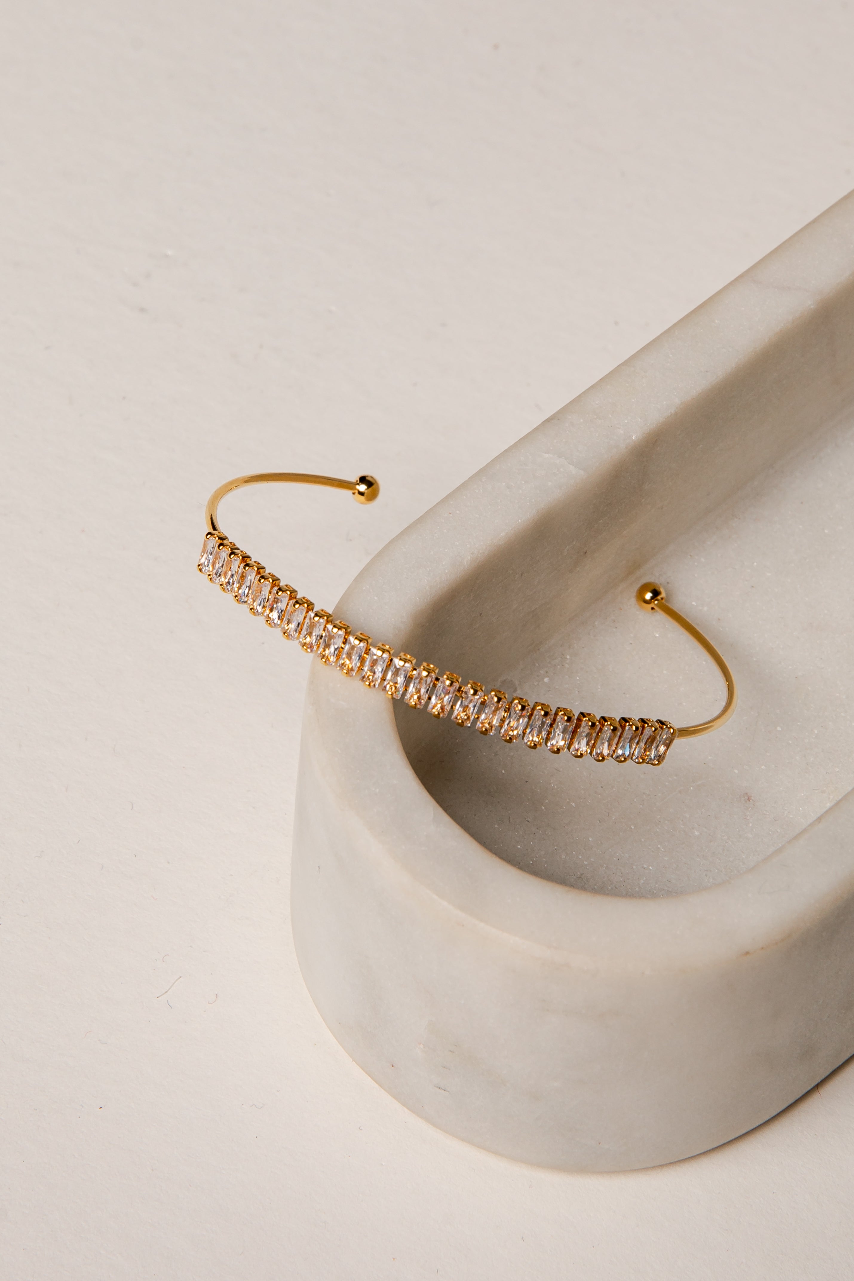 Gold bracelet with clear stones on a marble surface