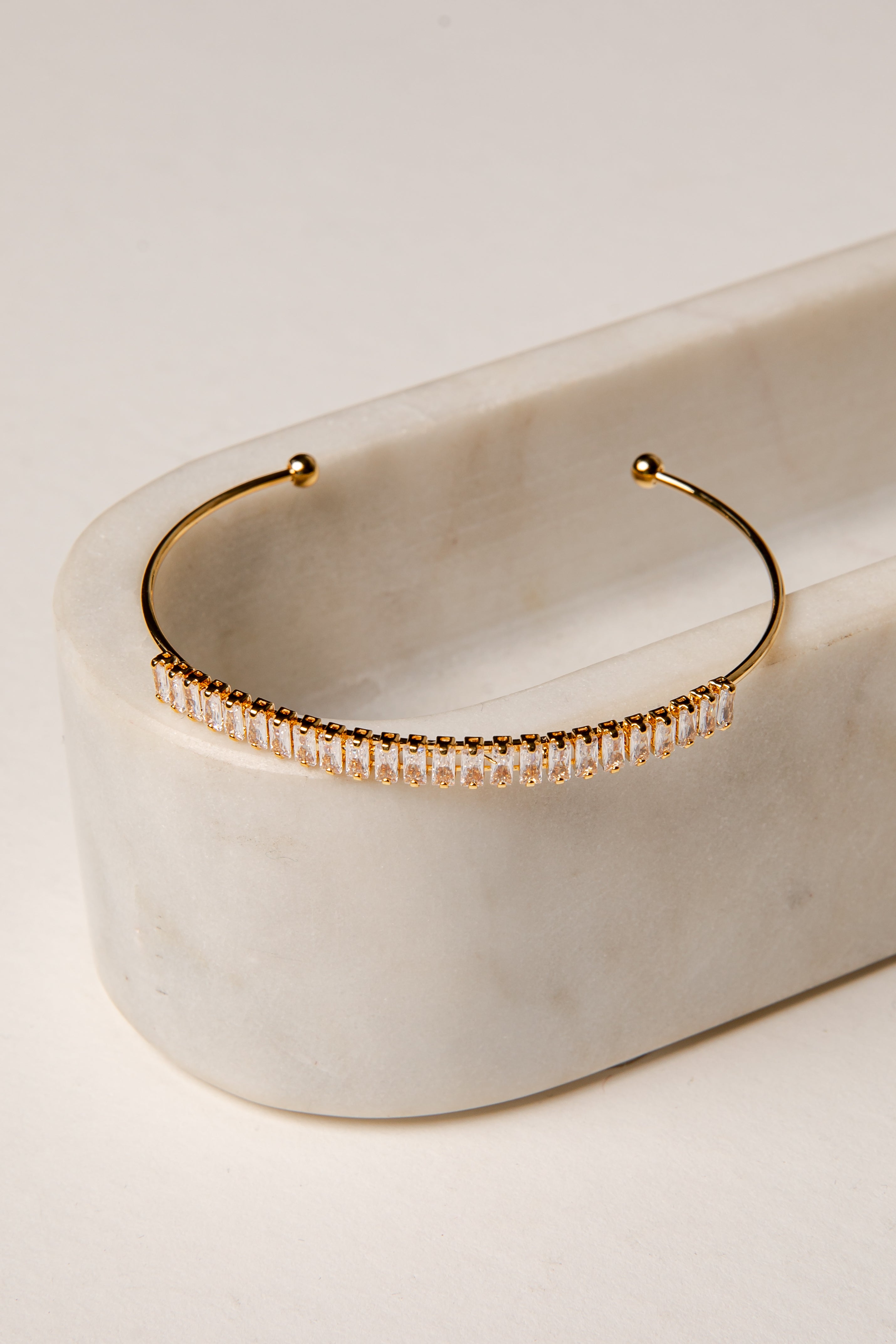 Gold hoop earring with embedded stones on a marble surface