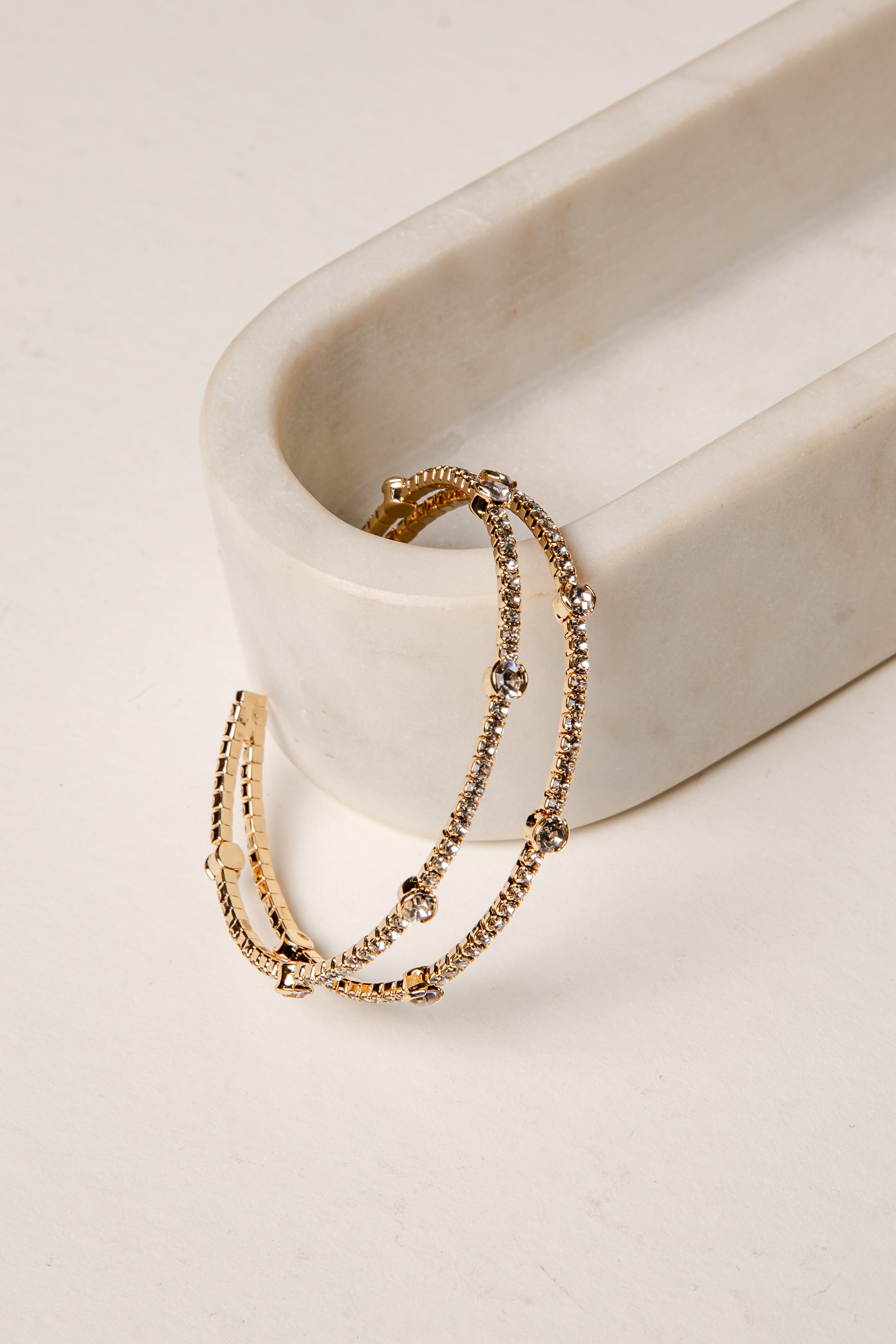 Gold bracelet on a white ceramic dish