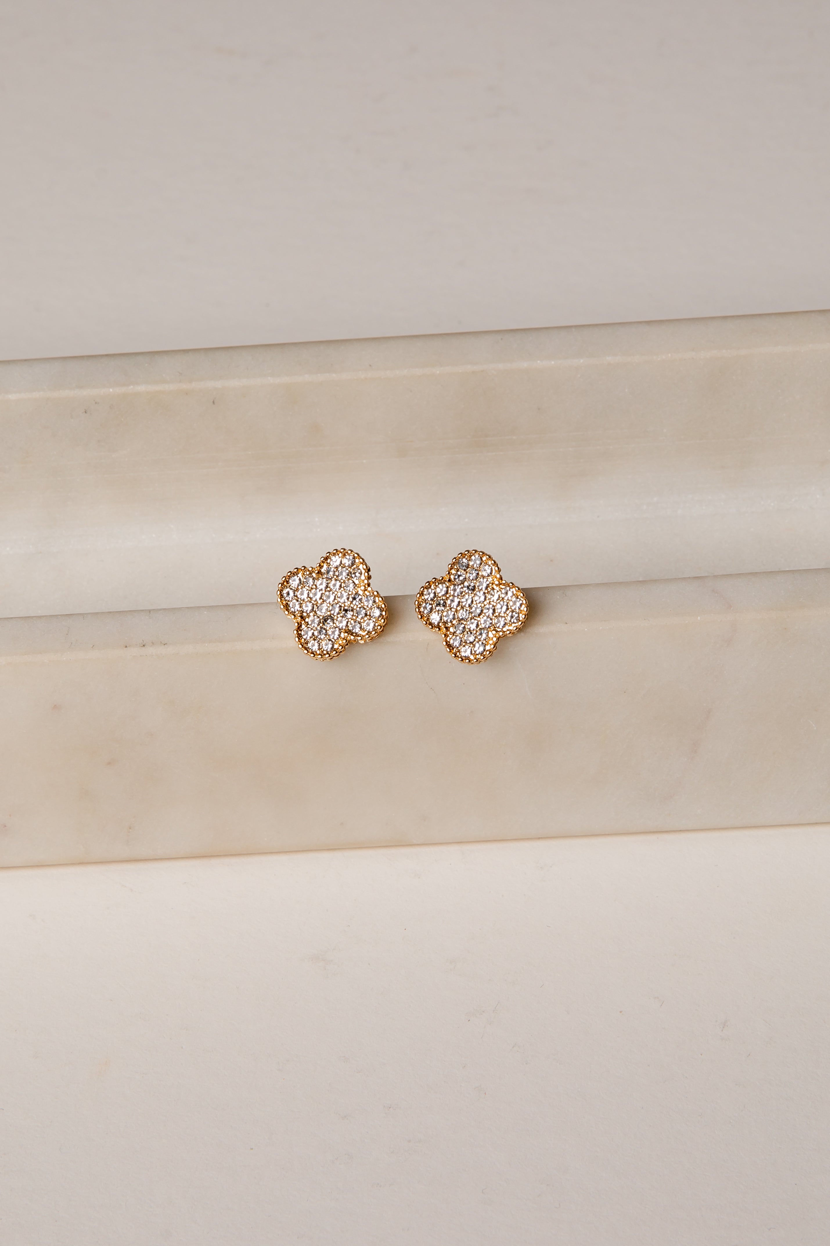 Rose gold floral earrings on a beige surface