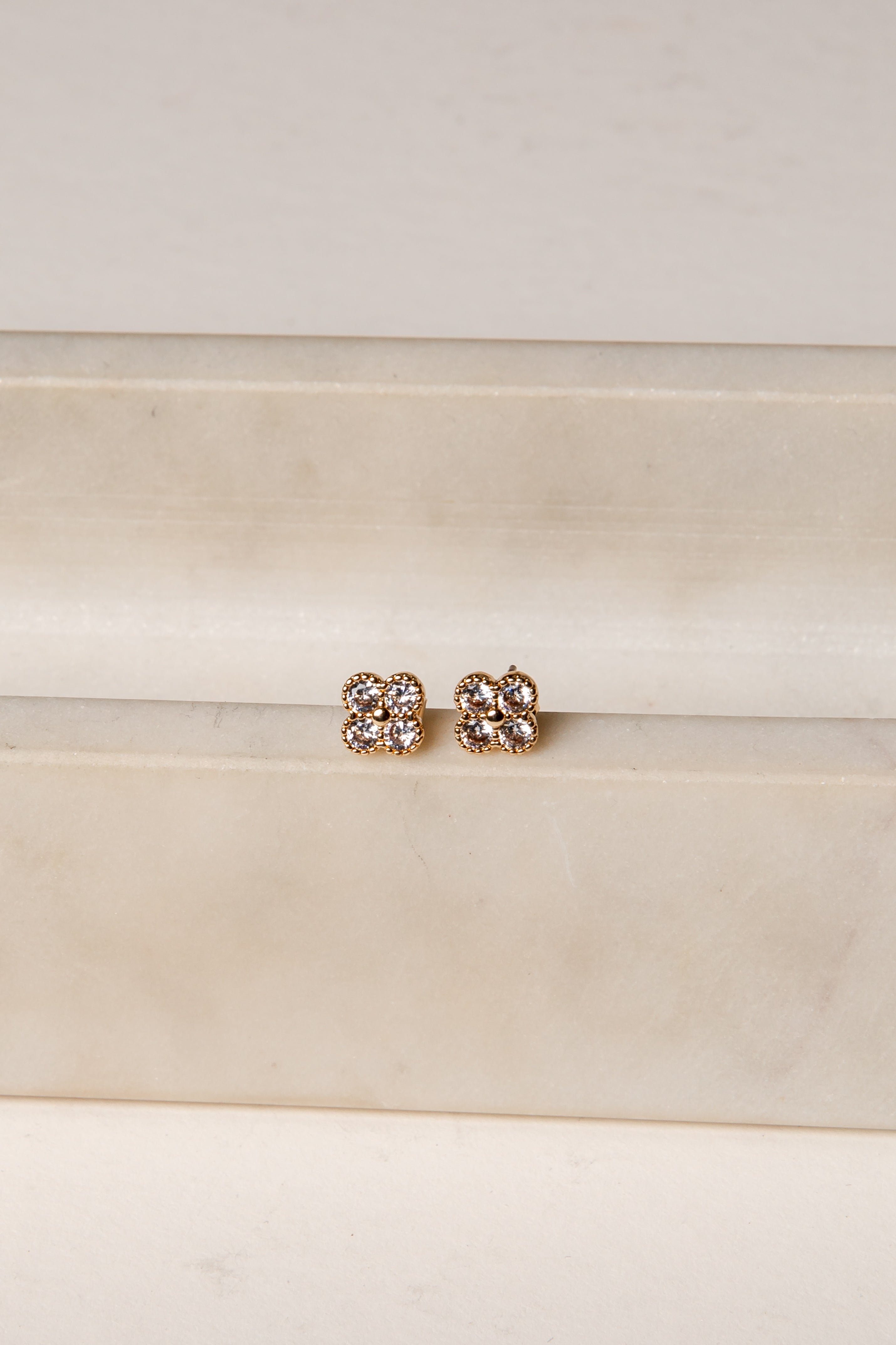 Pair of gold earrings with clear stones on a white background