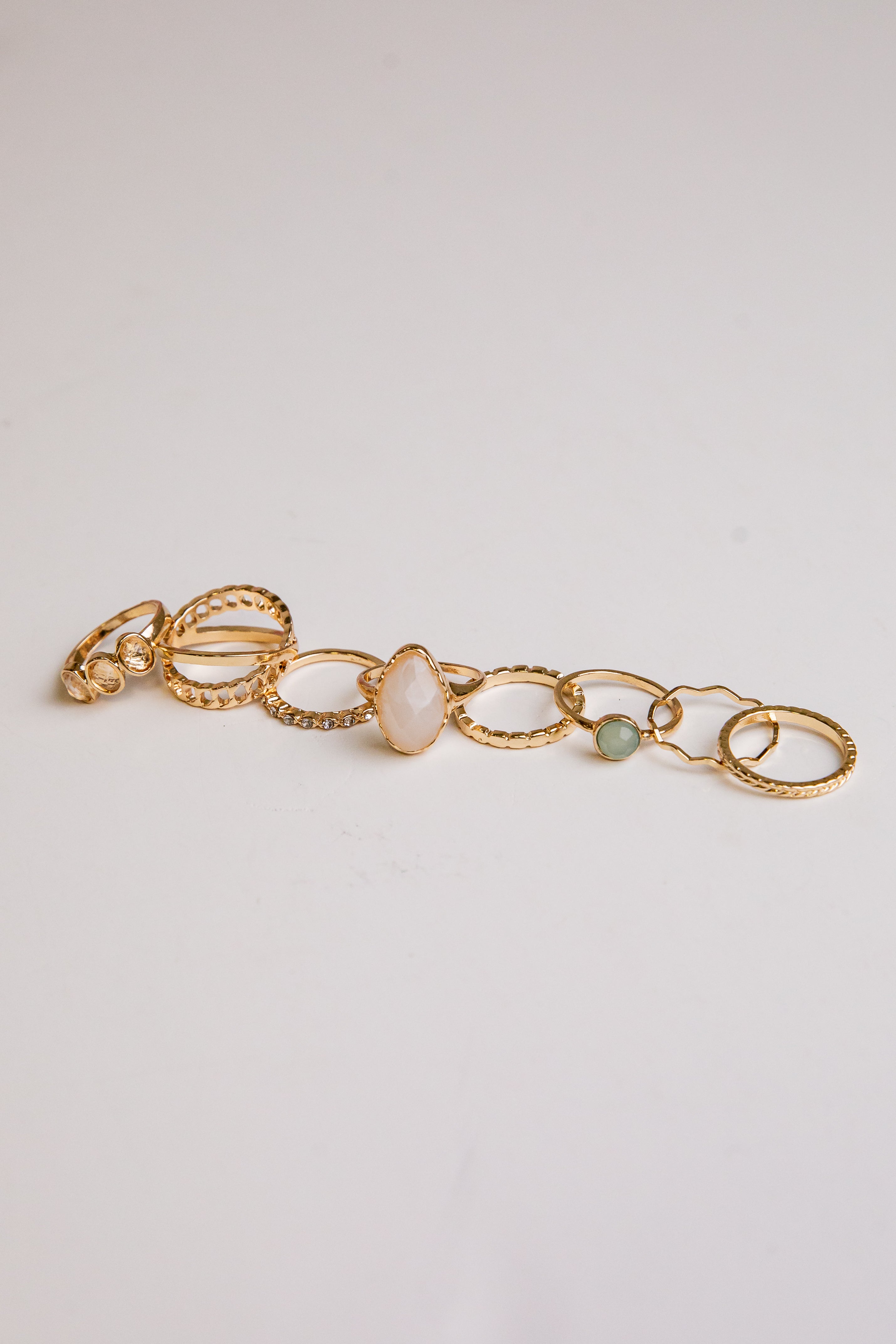 Gold bracelet with circular links and stones on a light gray background