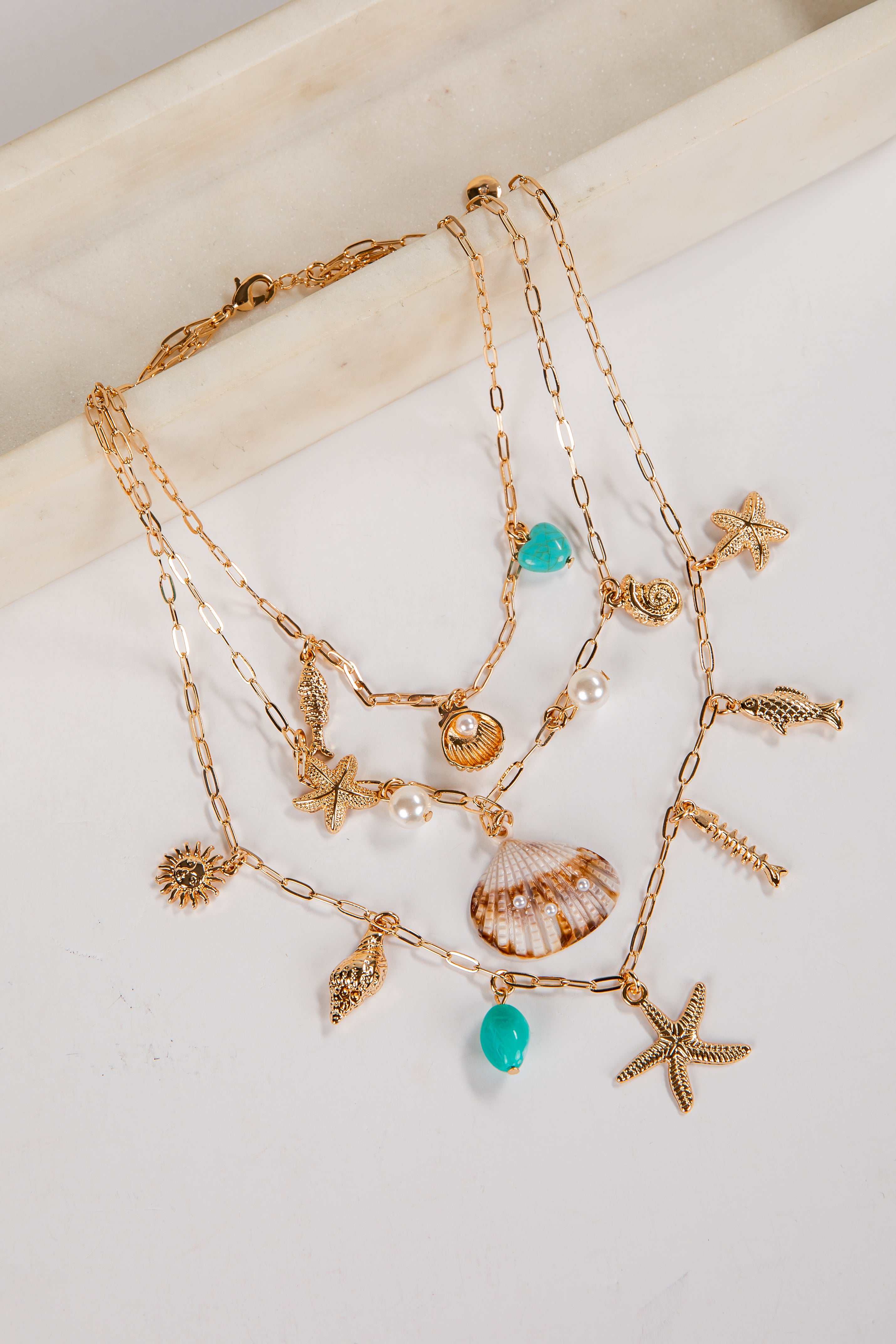 Gold necklaces with various charms on a white surface