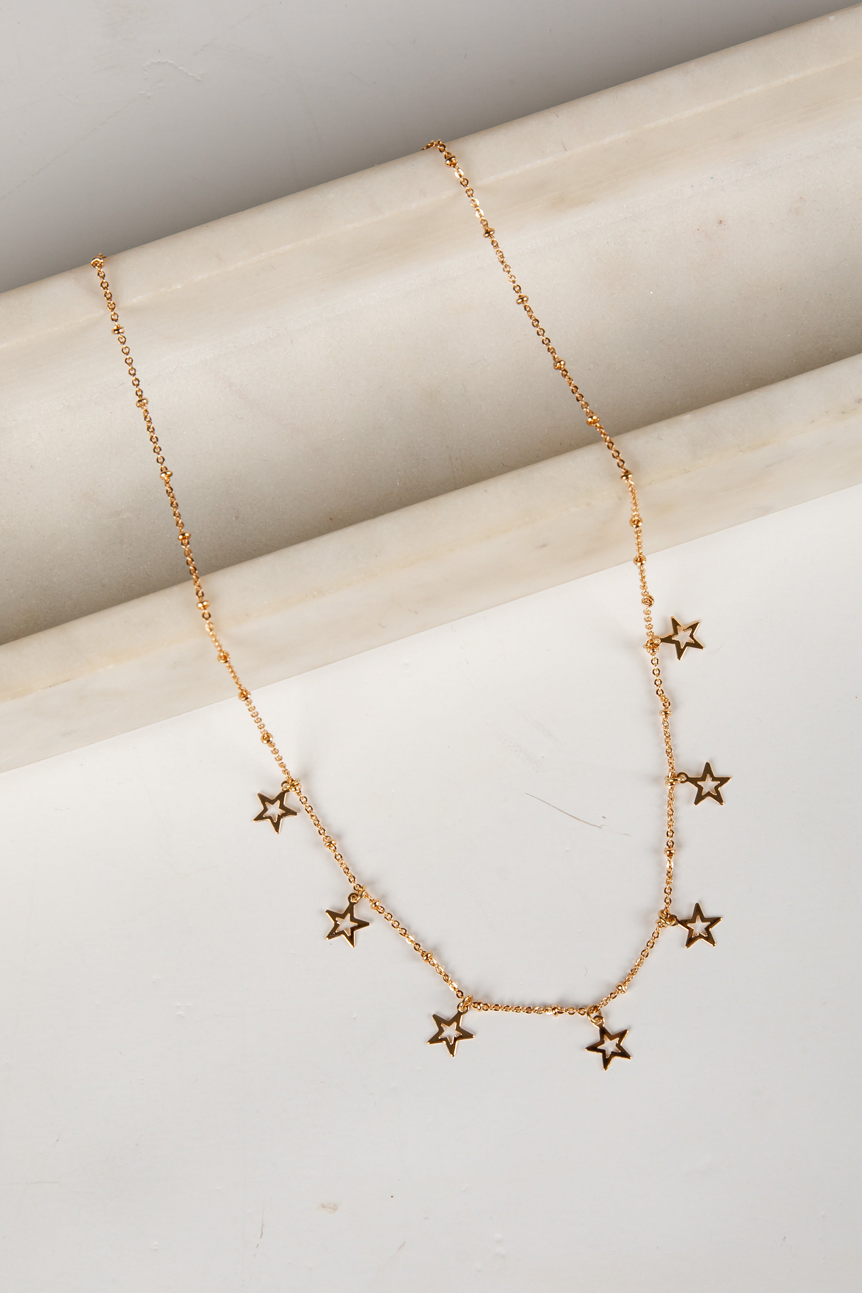 Gold star necklace on a light wooden surface