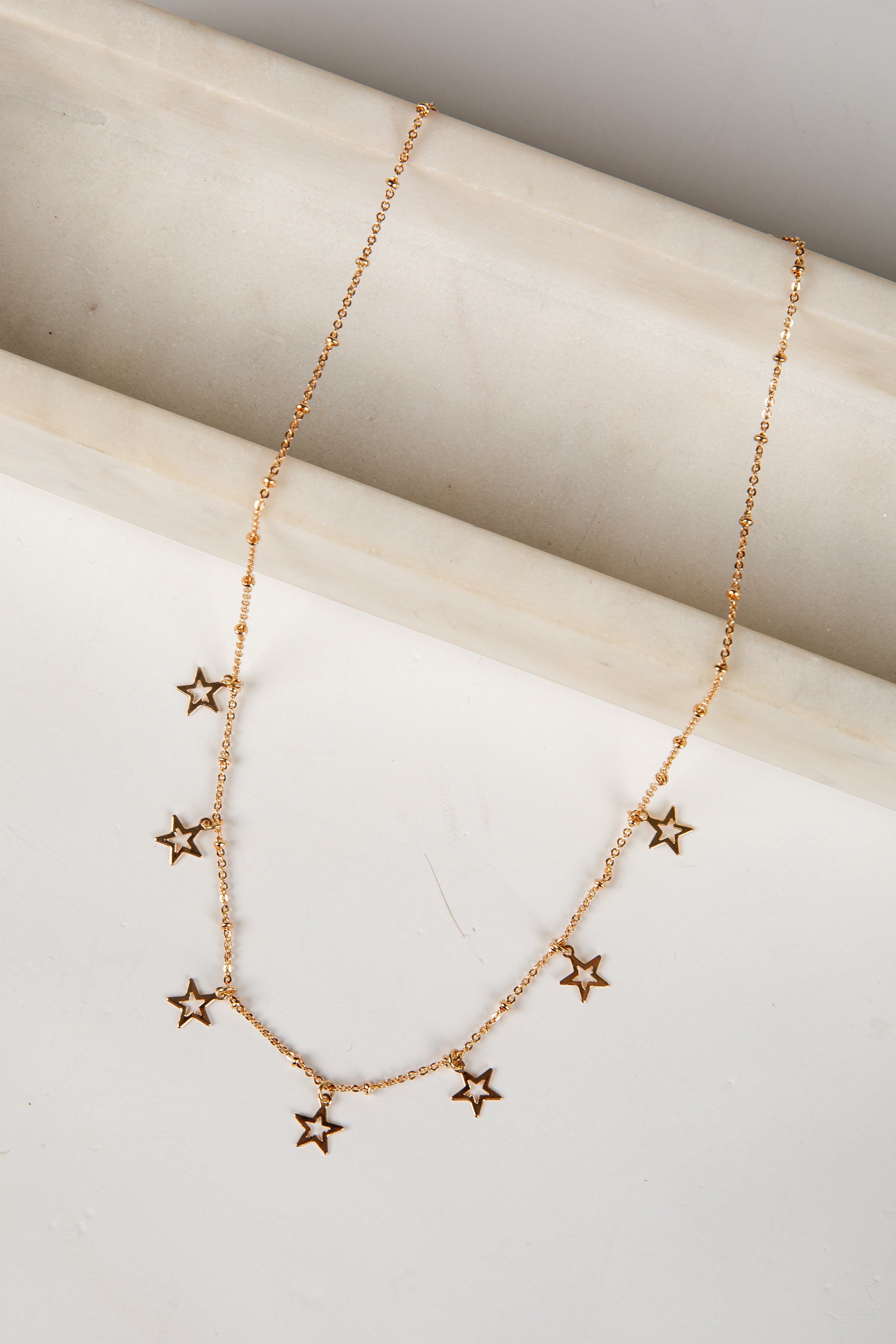Gold star necklace on a light wooden surface