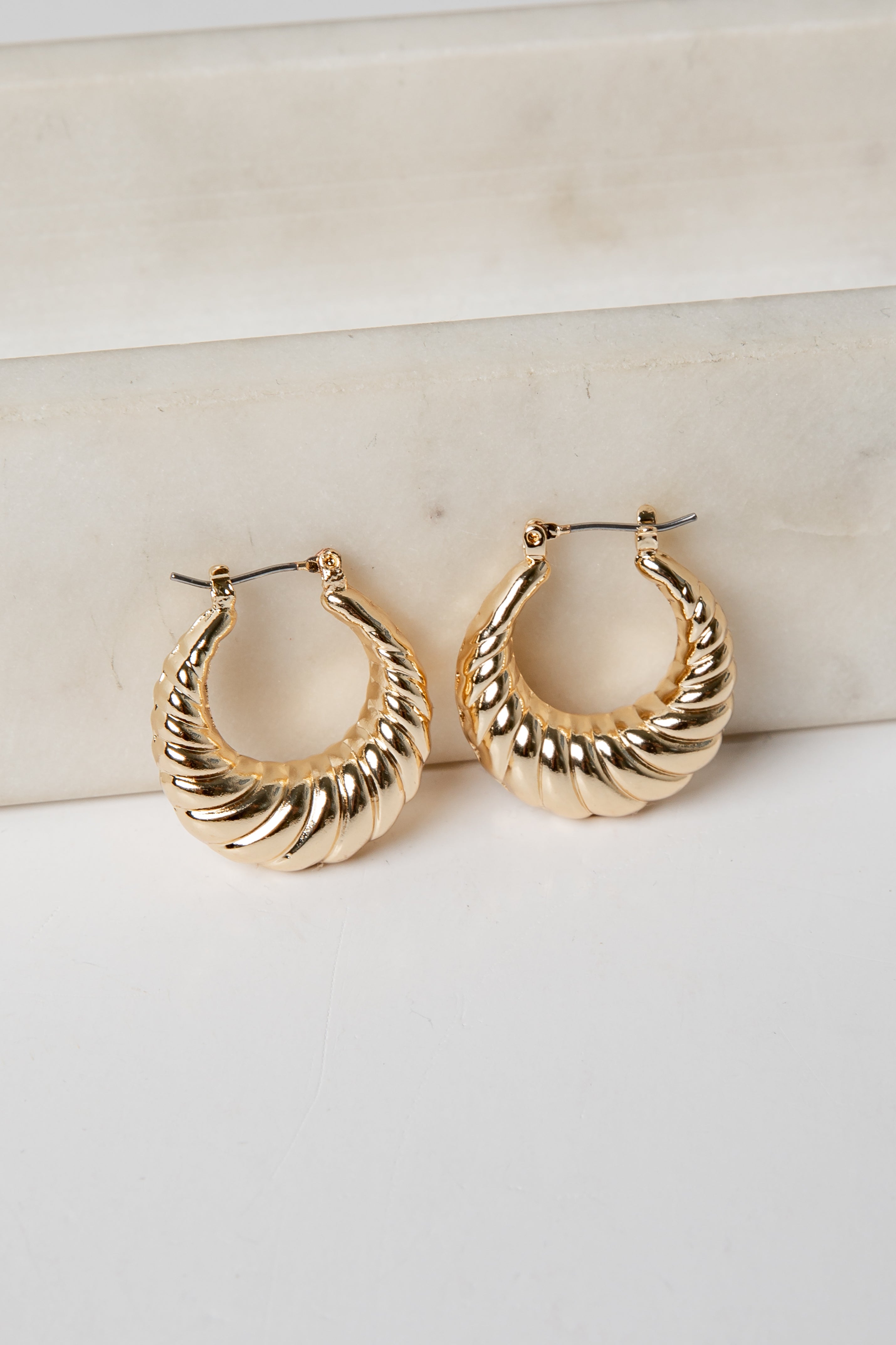 Gold hoop earrings on a light background